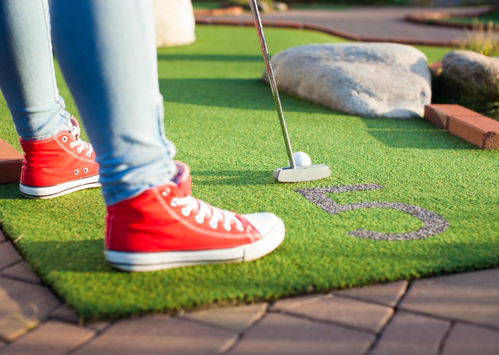 Woman playing mini golf on a sunny summer day