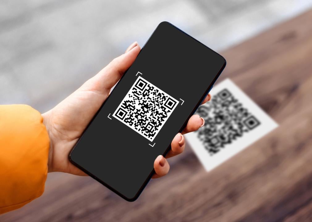 Hand holding black phone with QR code on the screen. 