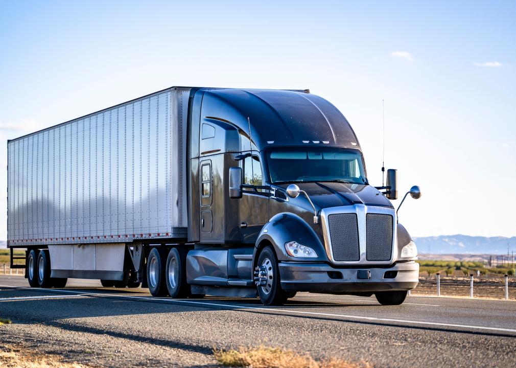 Black semitruck driving on open road.