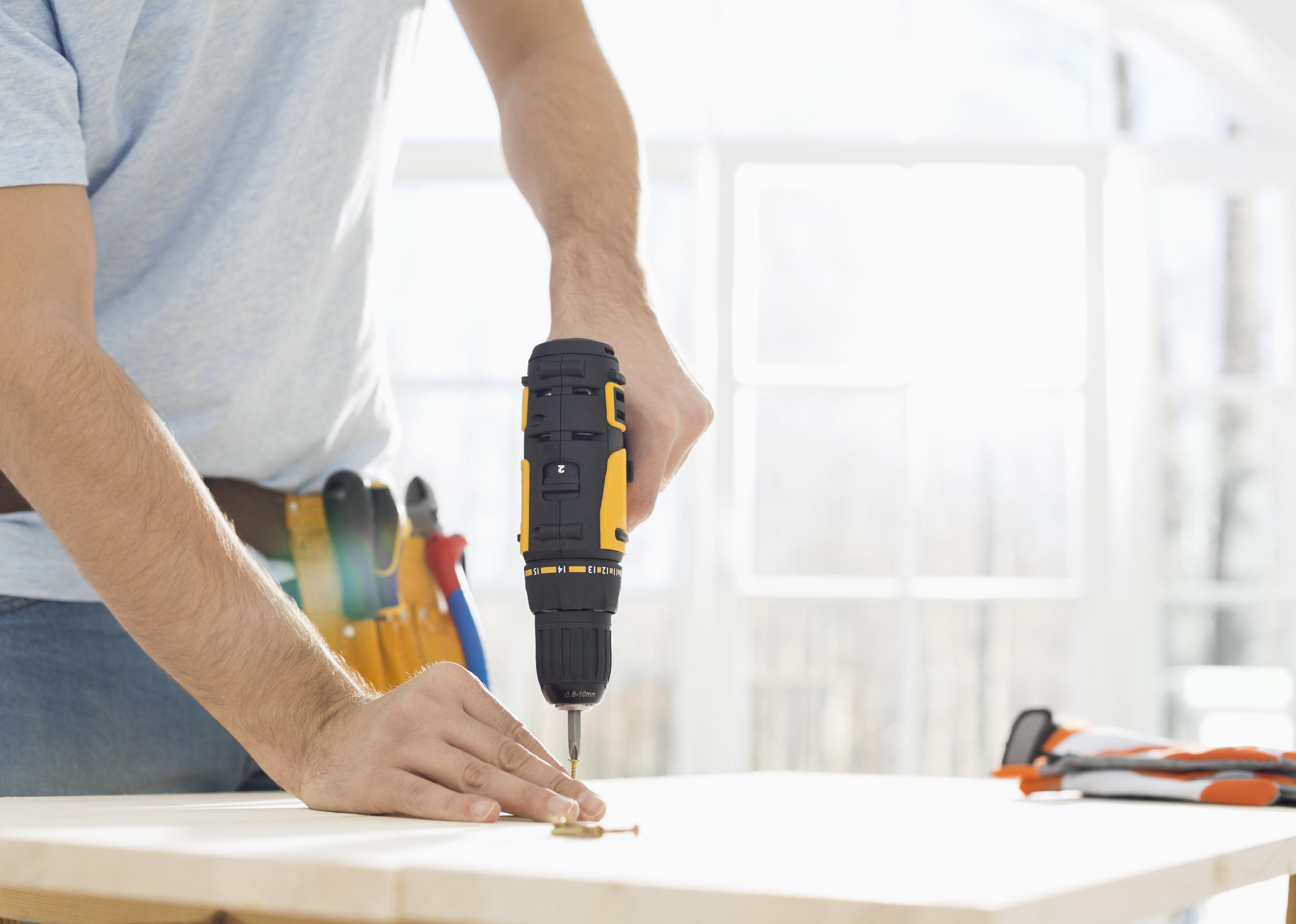 Midsection of man drilling nail on table