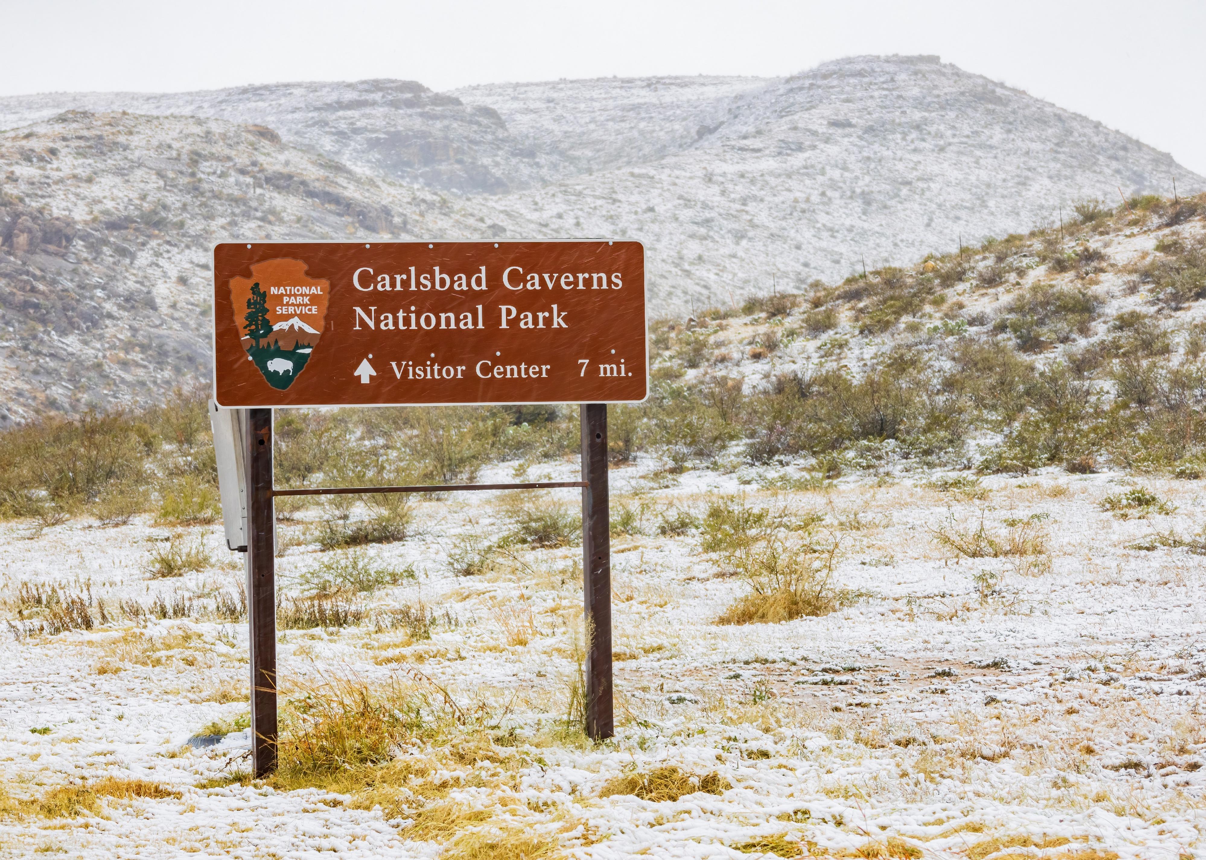 Carlsbad Caverns National Park sign amidst a blanket of snow.