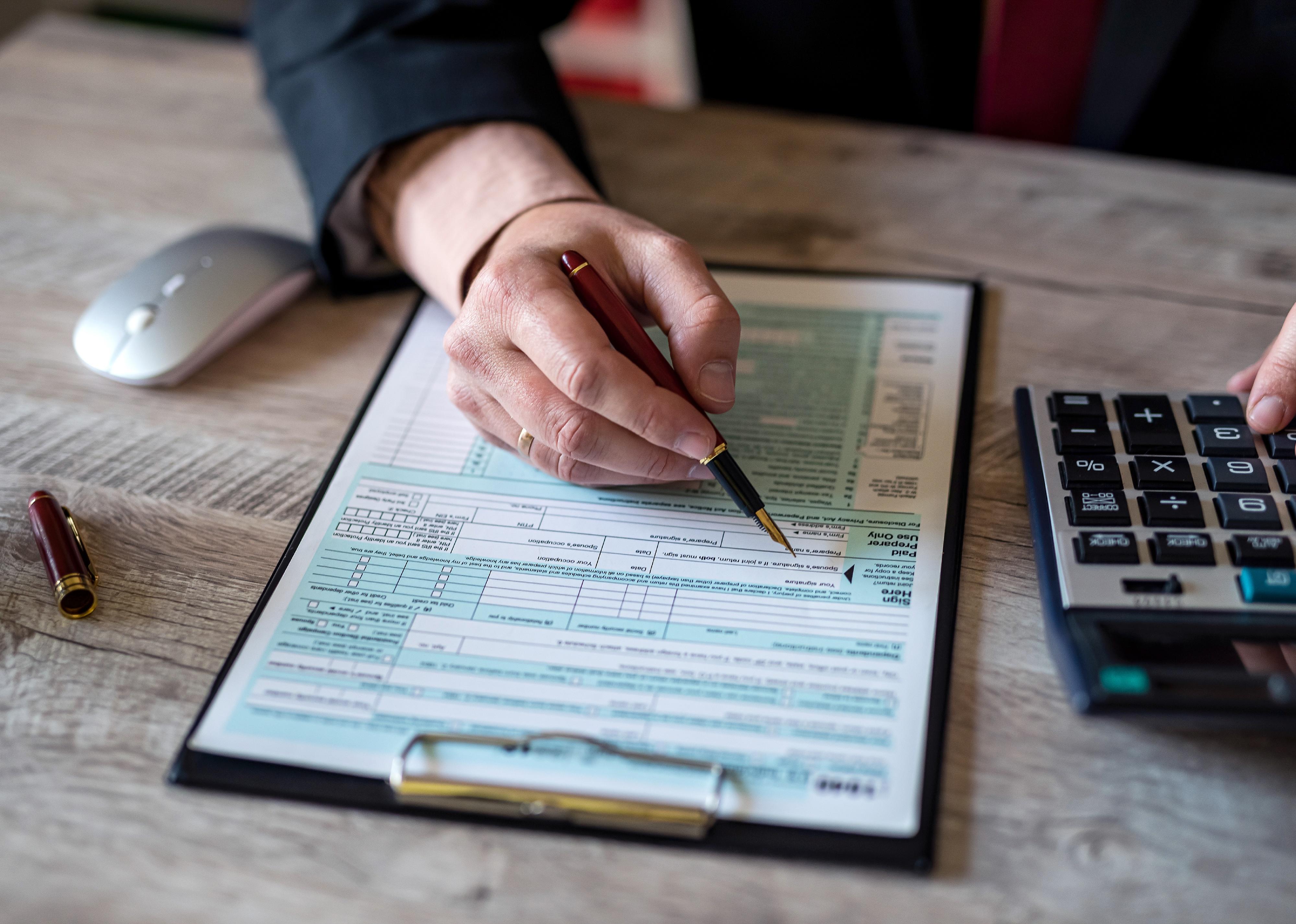 Businessman man in classic suit works with US tax form documents.