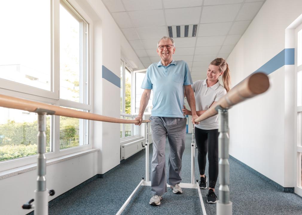 Senior patient and physical therapist doing rehabilitation walking exercises.