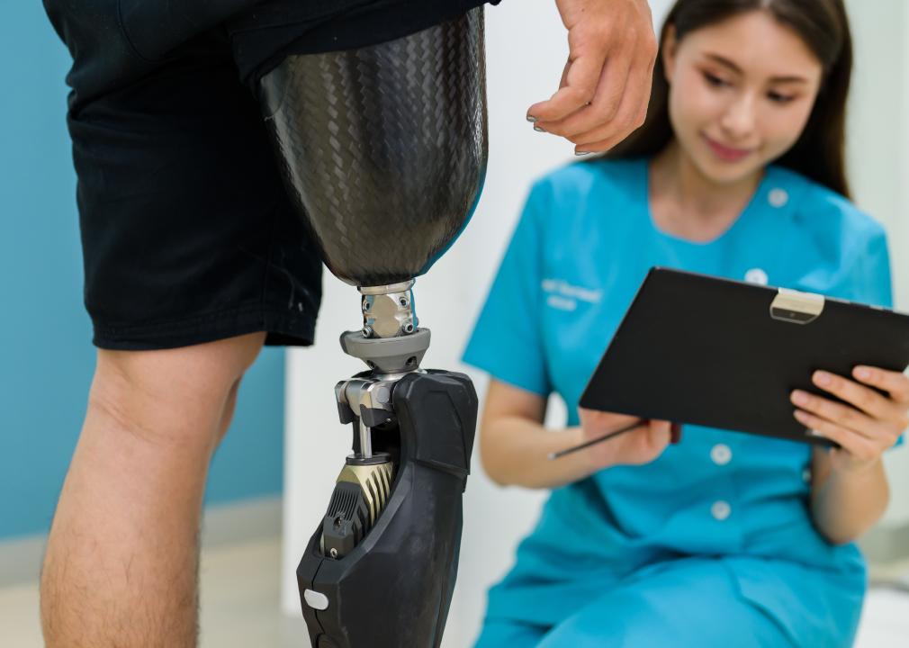 Prosthetist nurse checking prosthetic leg of patient.