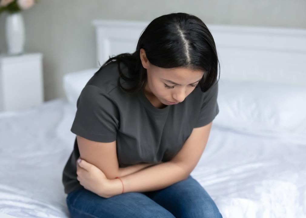 Girl on bed holding stomach.