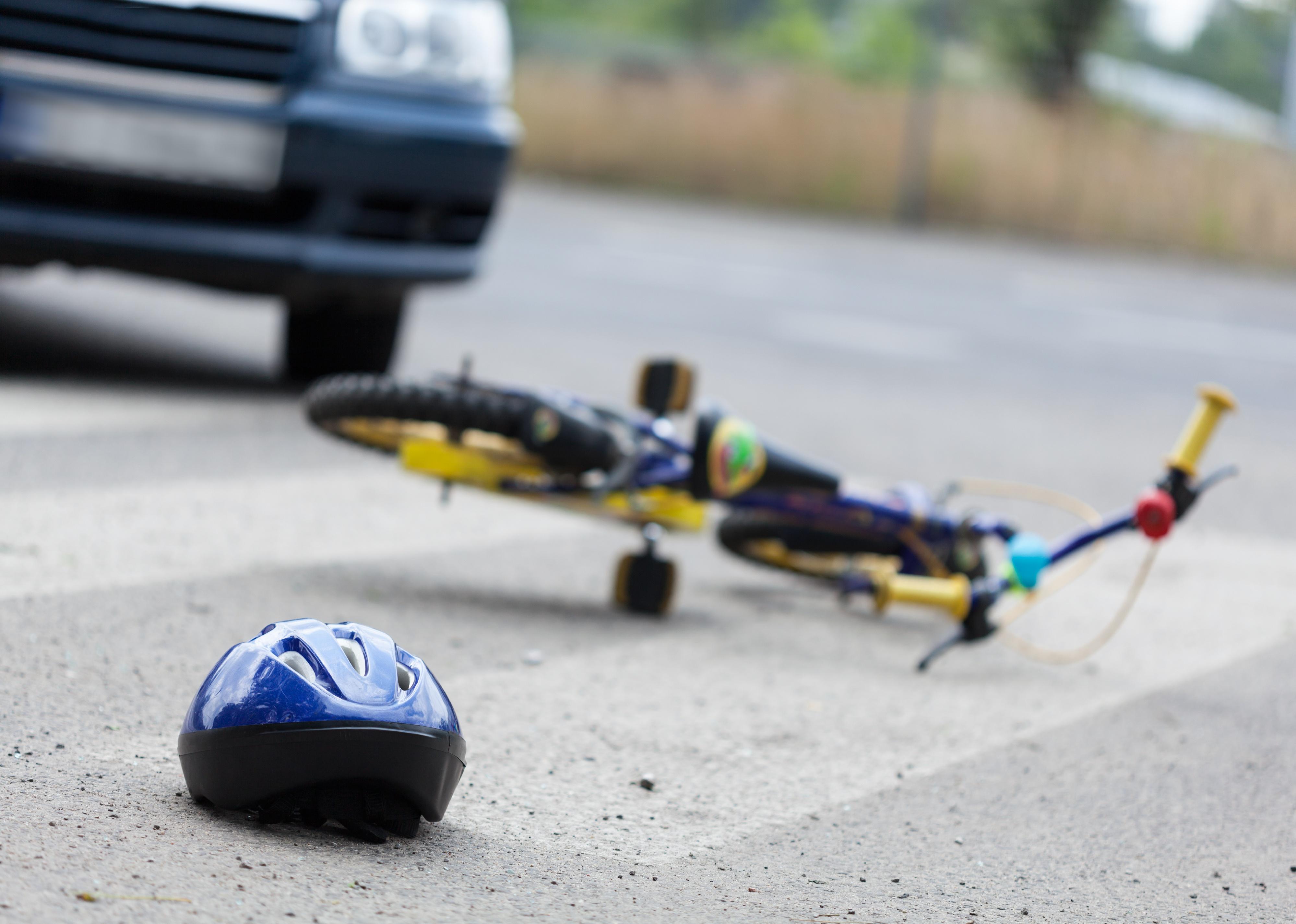 A small bike and a helmet lying on the road.