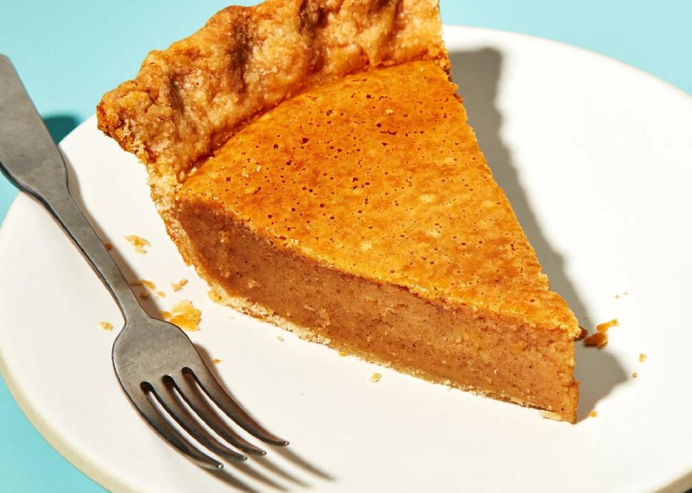 A slice of bean pie on a white plate with a fork.