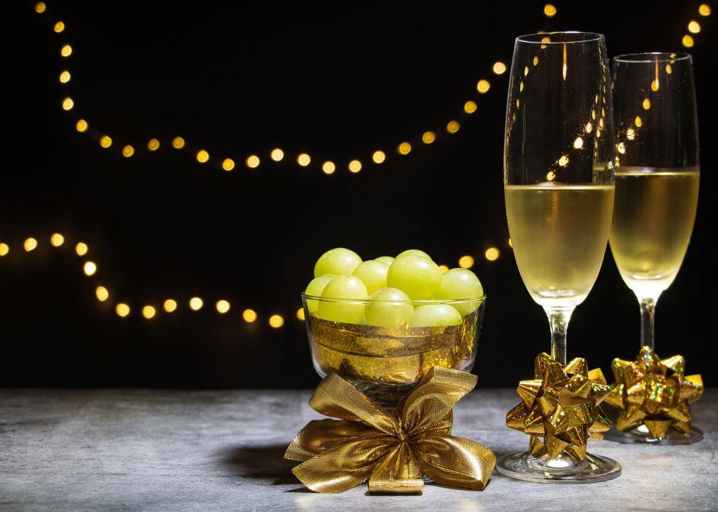 Two glasses of champagne with twelve grapes.