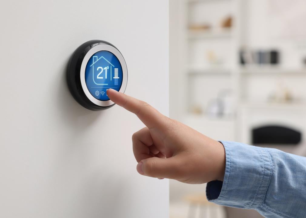 Woman using thermostat indoors.