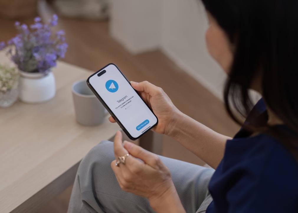 A woman looks at the Telegram application icon on an Apple iPhone.