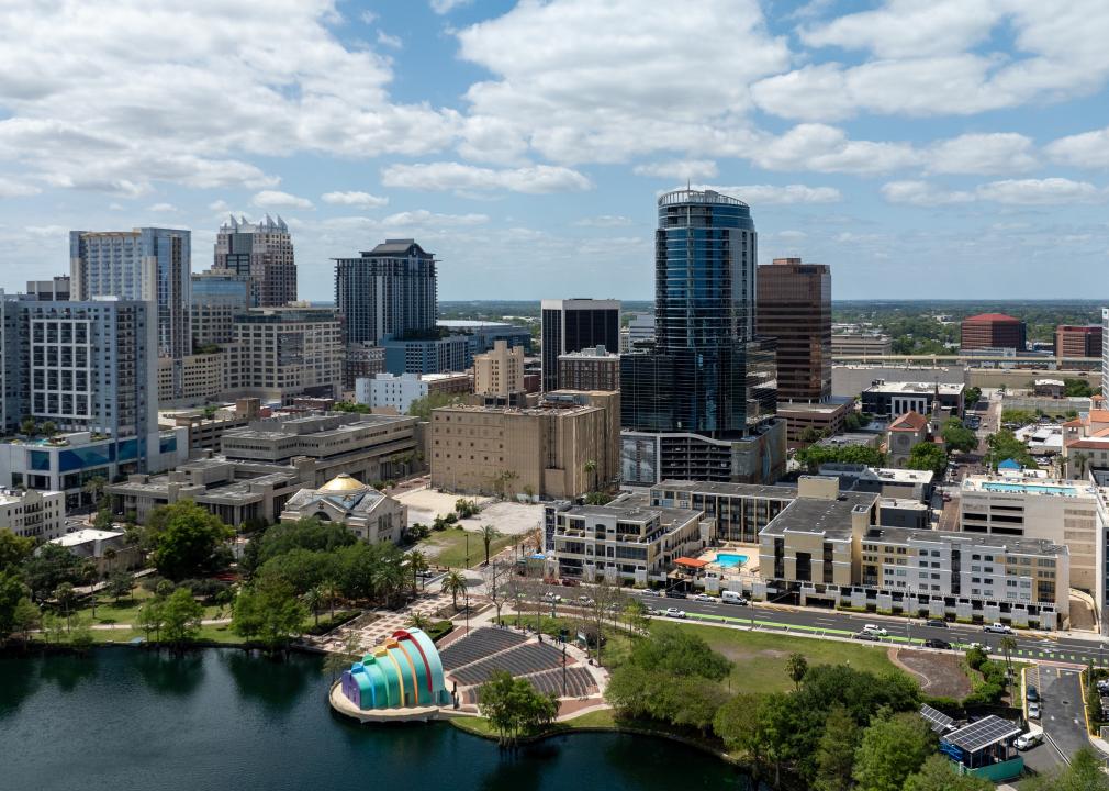 Downtown Orlando commercial and residential buildings under a partly cloudy sky near the water.