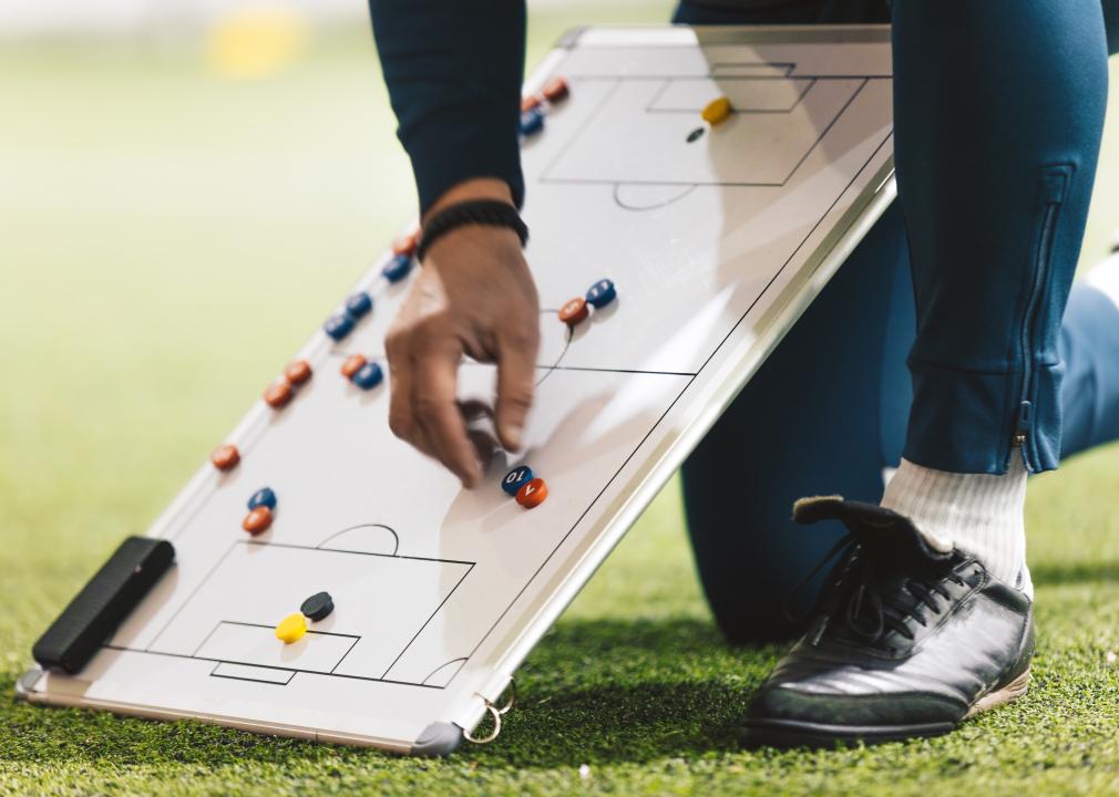 A coach using a white board with a soccer field drawn on to show plays.