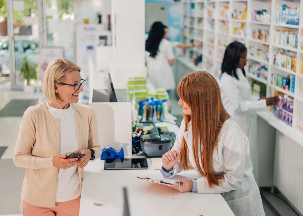 A woman chats with a pharmacist at a pharmacy counter.