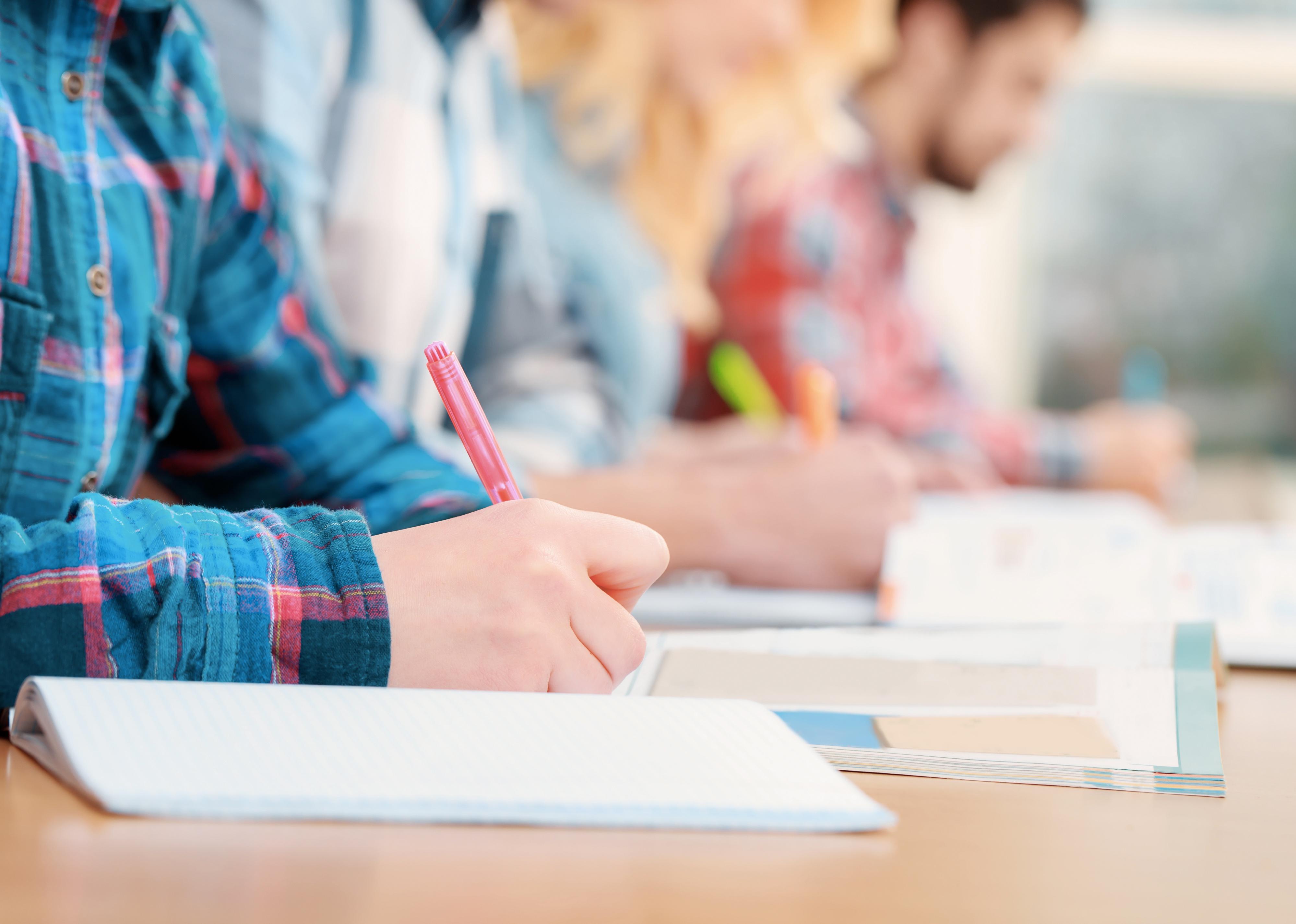 Cropped view of students writing a test in books