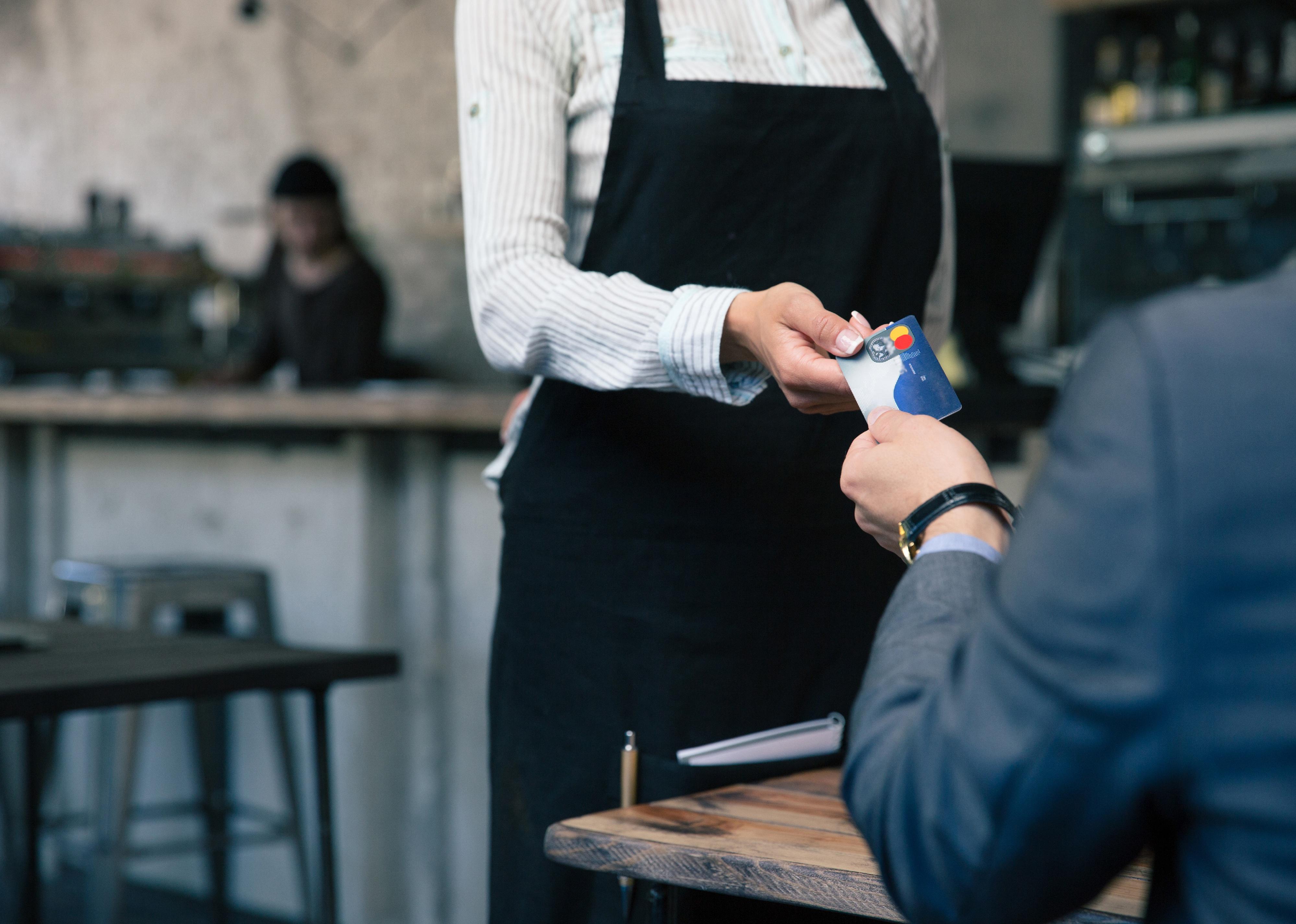 Closeup image of a man giving credit card to waiter in cafe