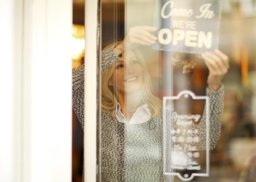 Smiling woman standing behind her clothing store shop open window