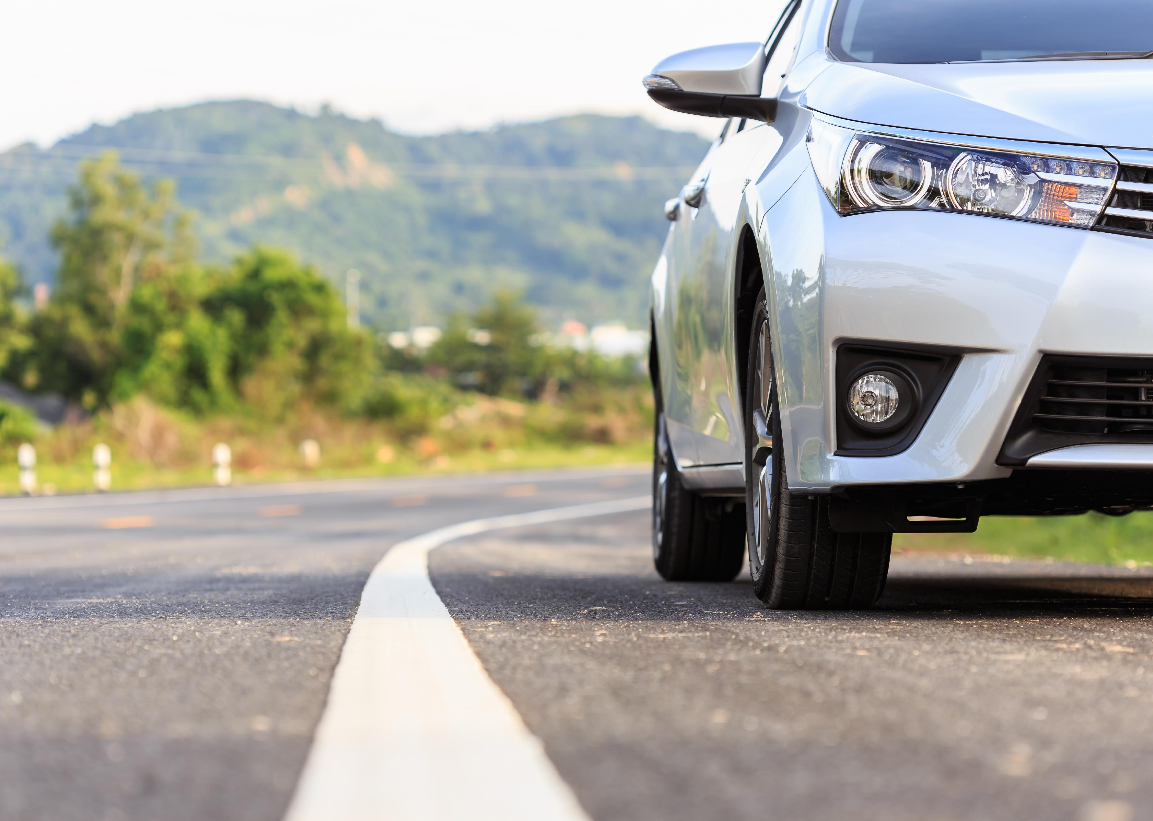 Close-up front of new silver car parking on the asphalt road.