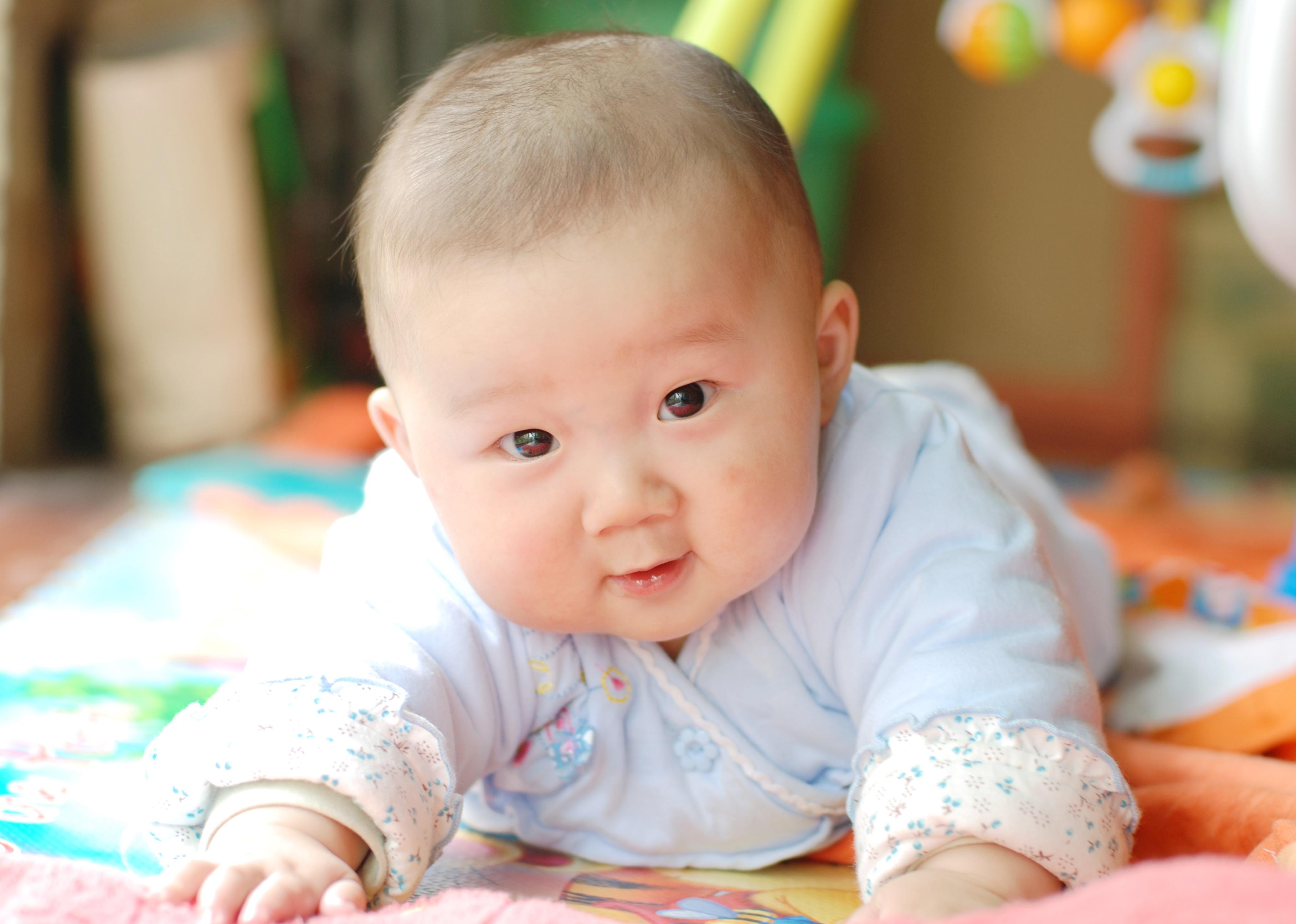 Baby lying on stomach on colorful bedding.