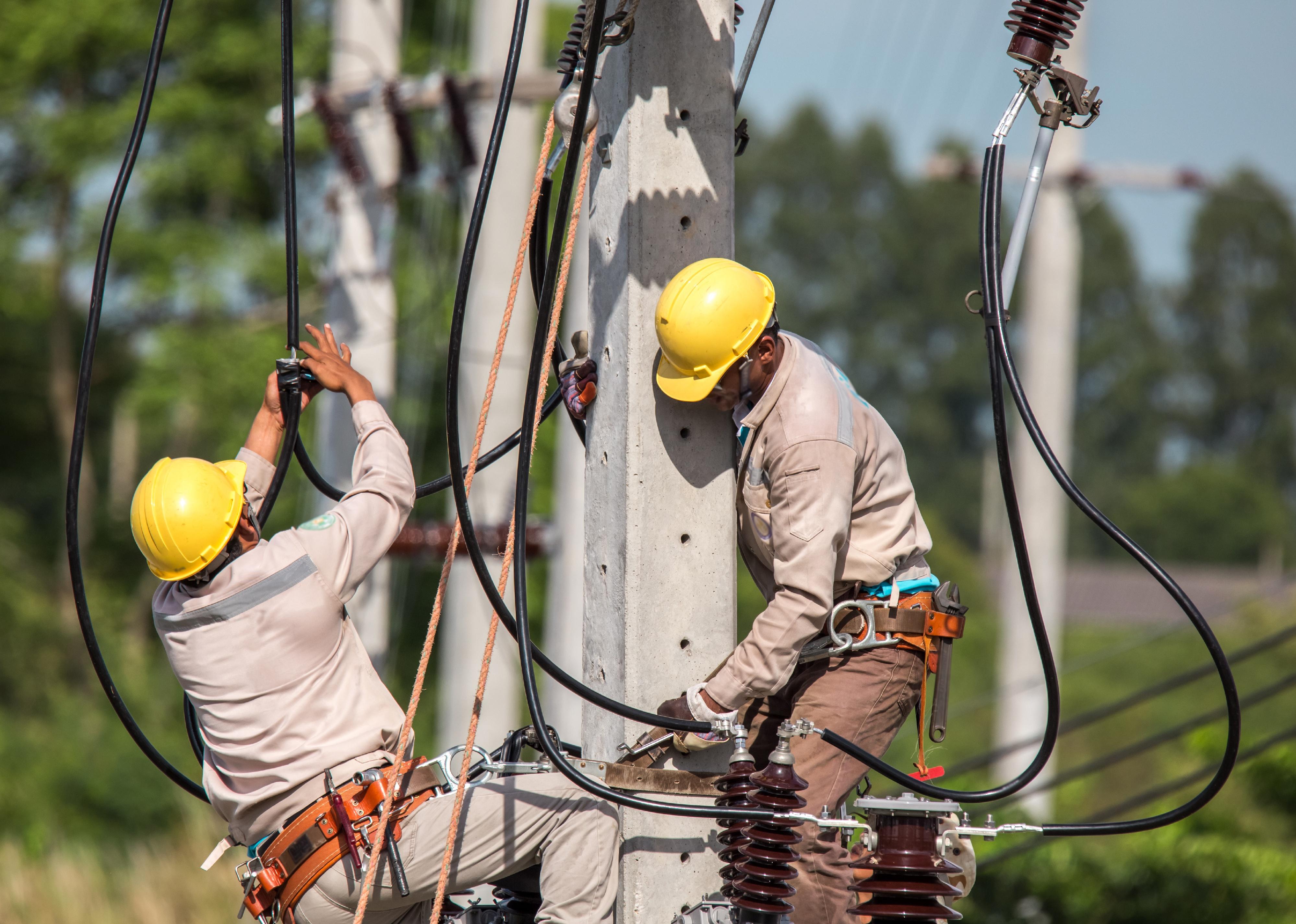 Two electricians working on a power line.