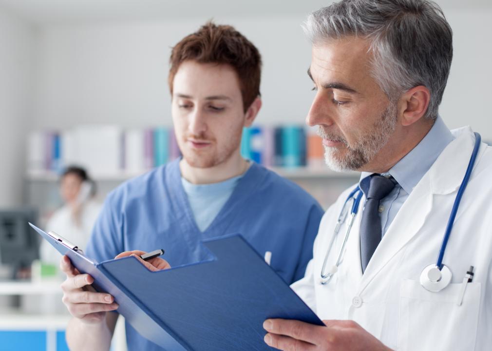 Doctor and practitioner examining patient's medical records on a clipboard.