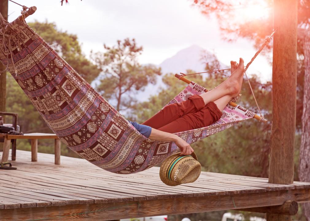 A person relaxes in an outdoor hammock as the sun sets