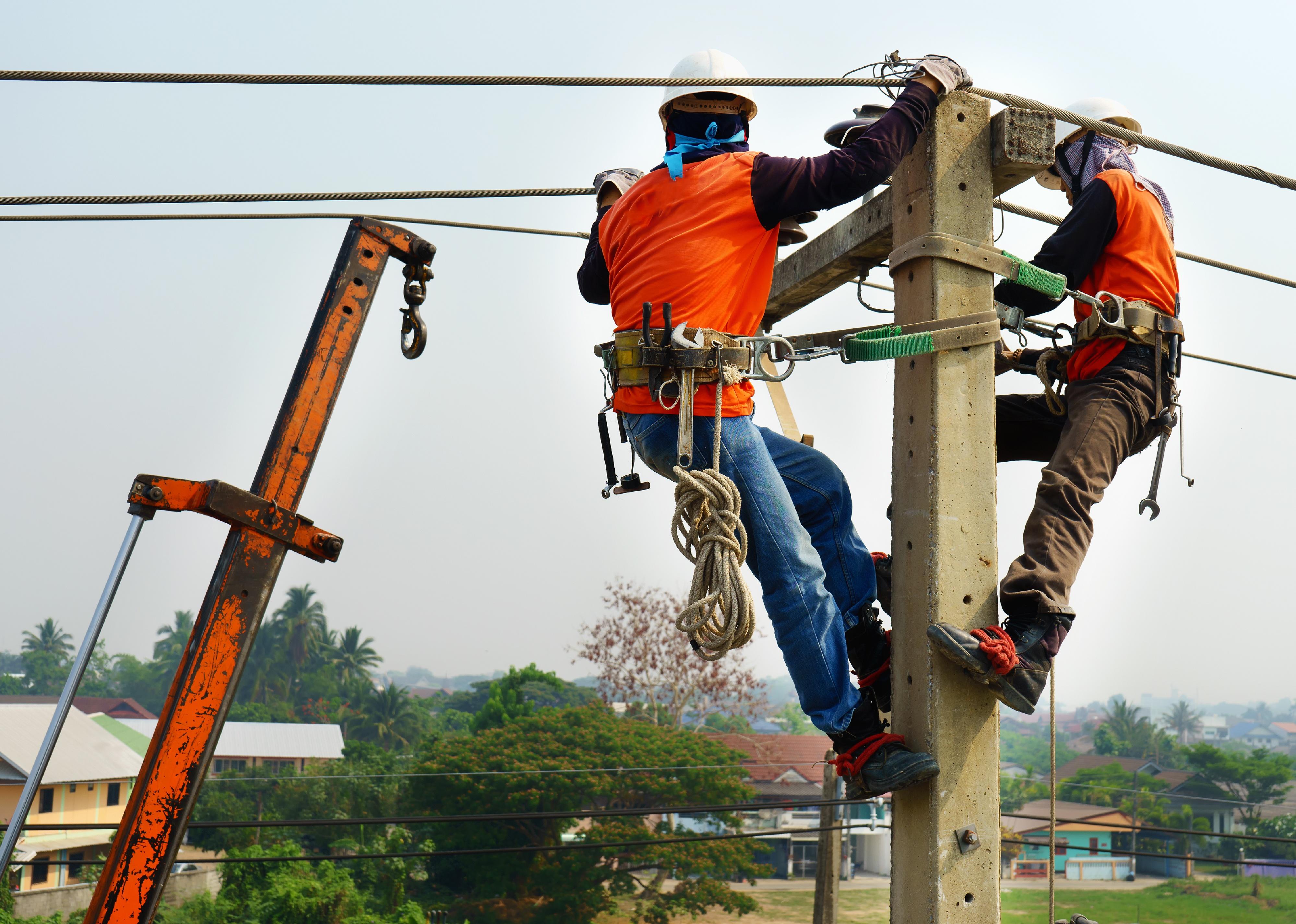 Electrician climbing up an electric power post.