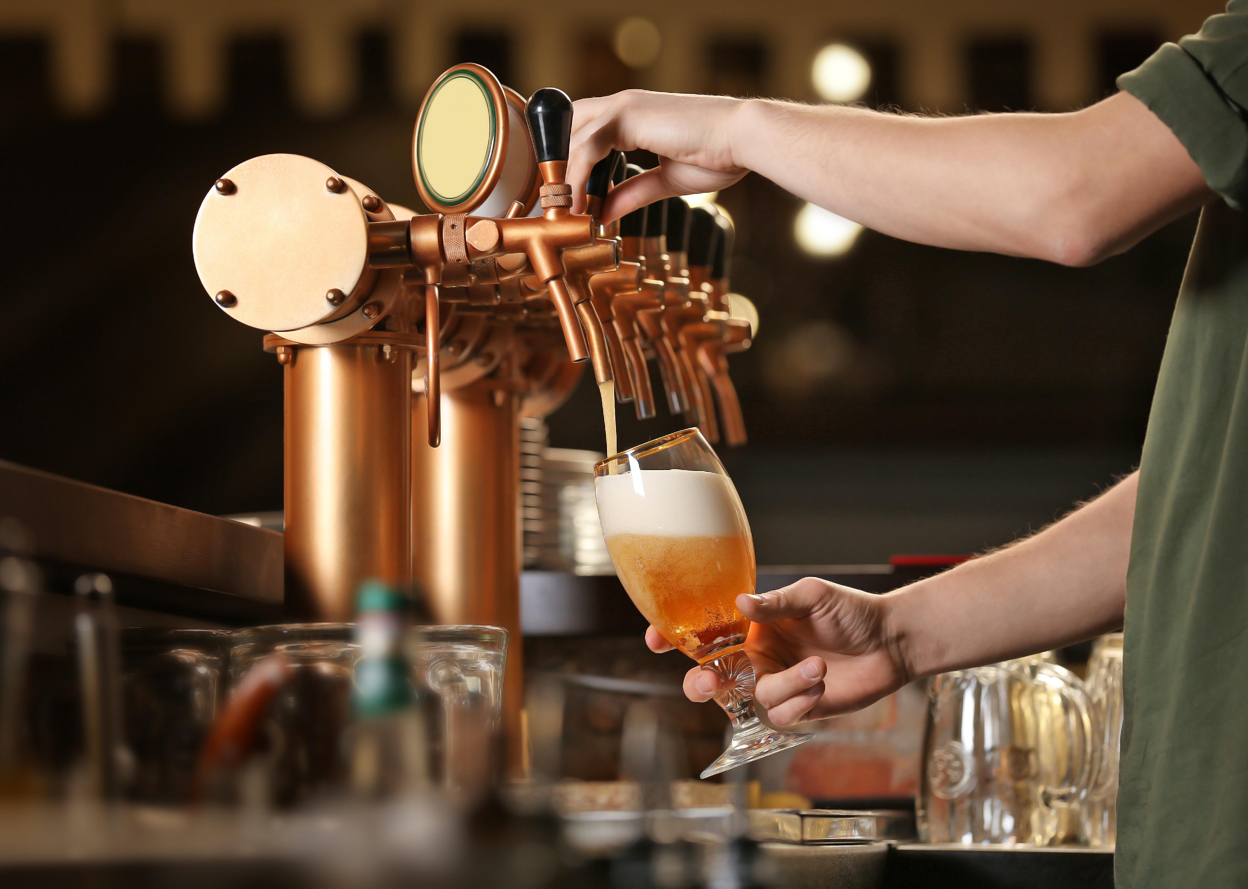 Barman hands pouring a lager beer in a glass