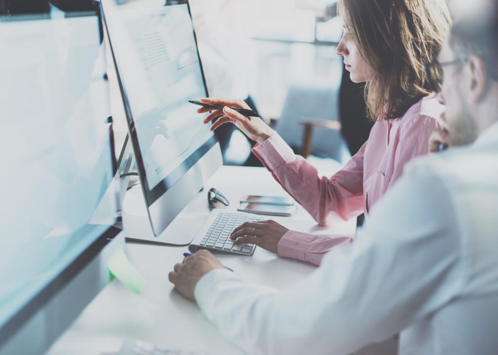 Coworkers in front of a computer in a modern office.