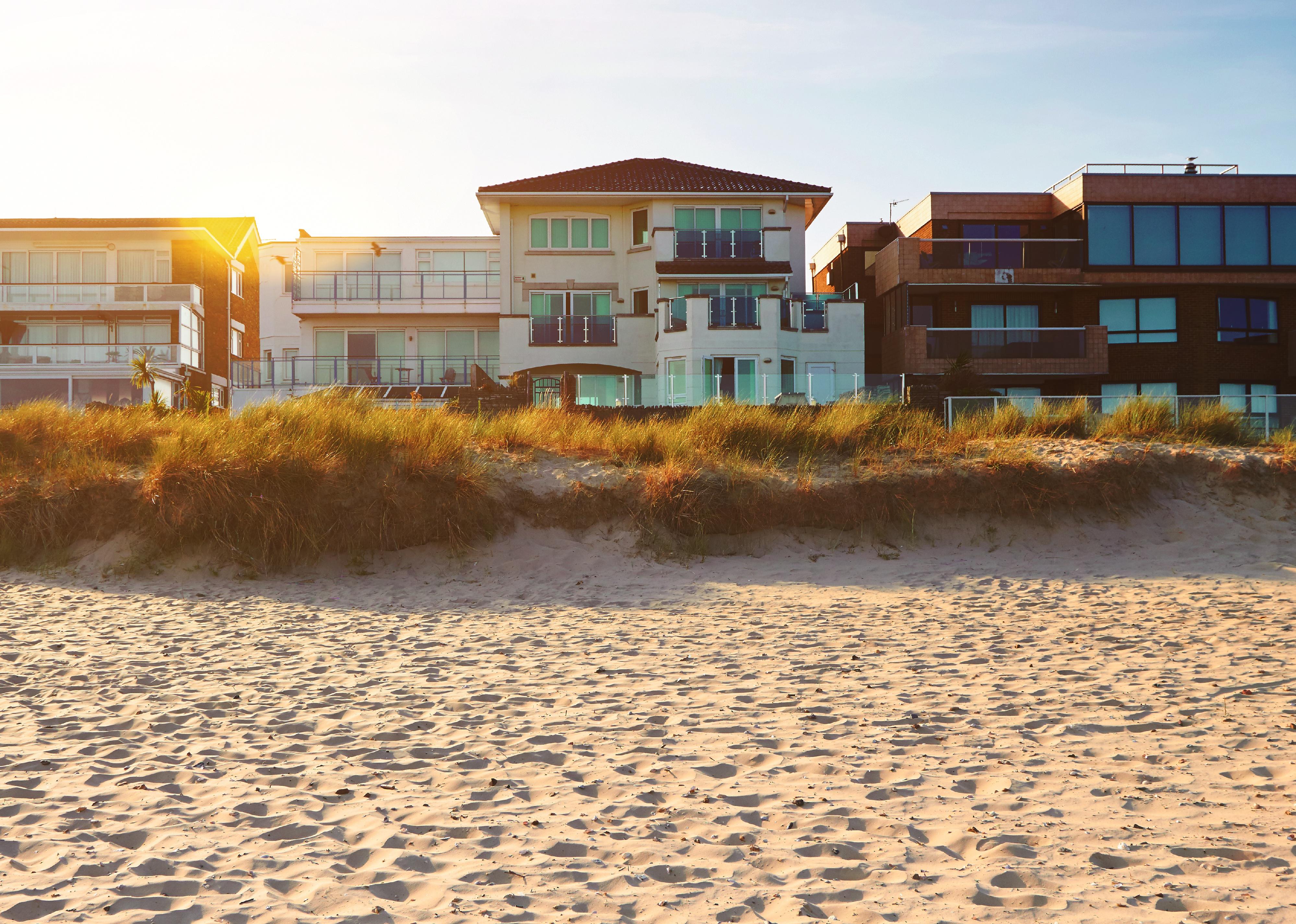 Front view of house on the beach and a setting sun.