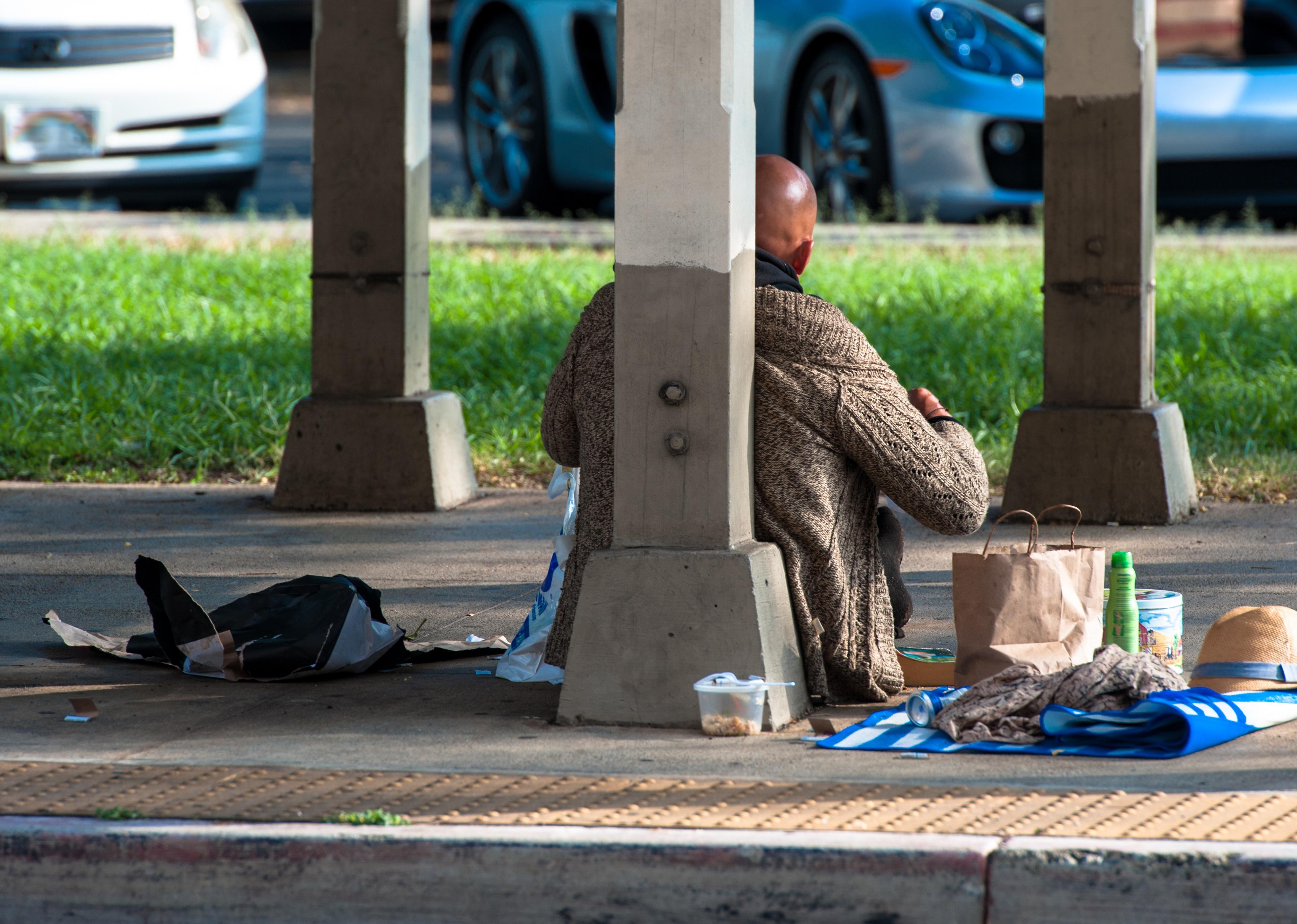 Homeless man sitting on the side of the street.