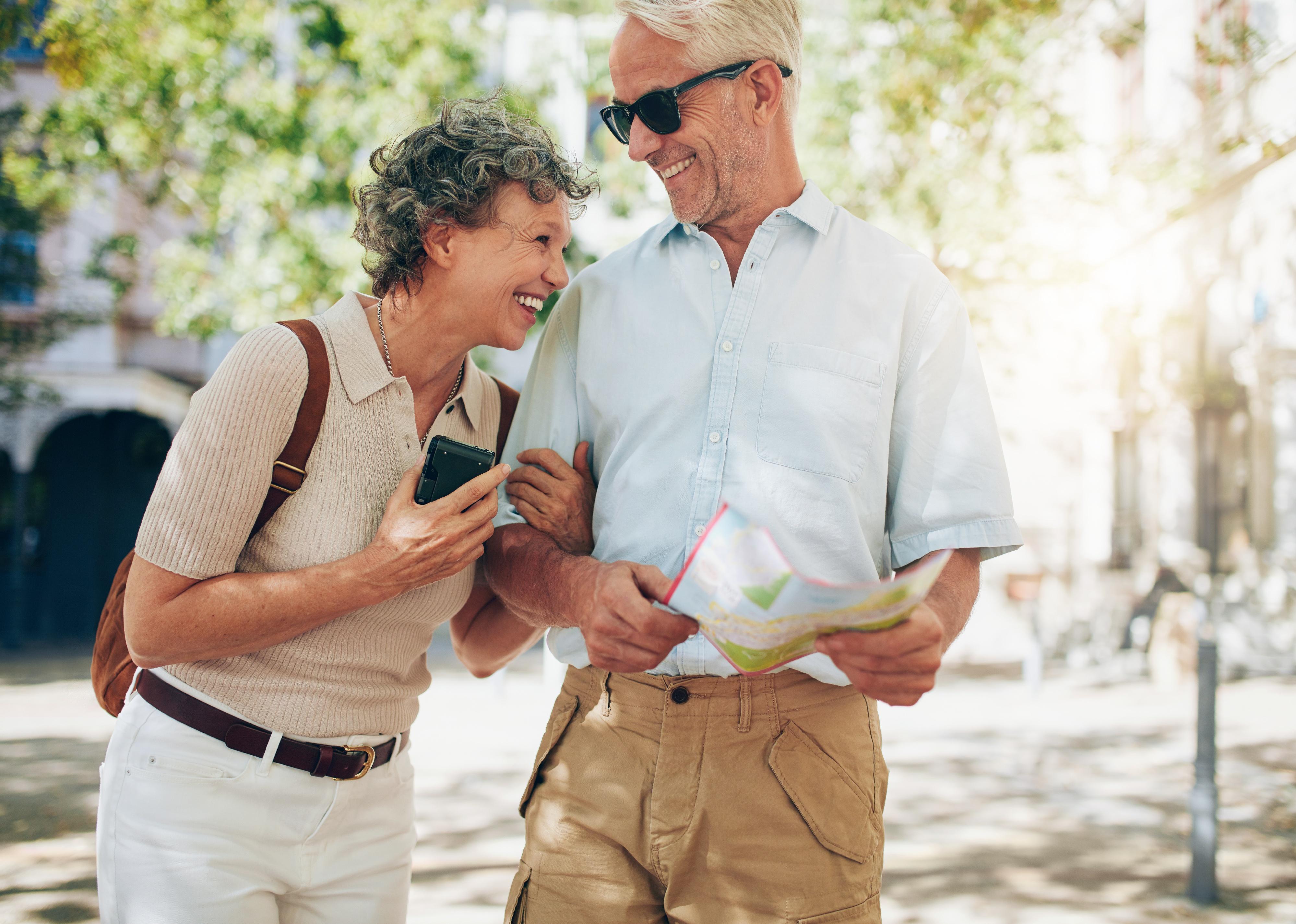 Retired couple walking around the town with a map.