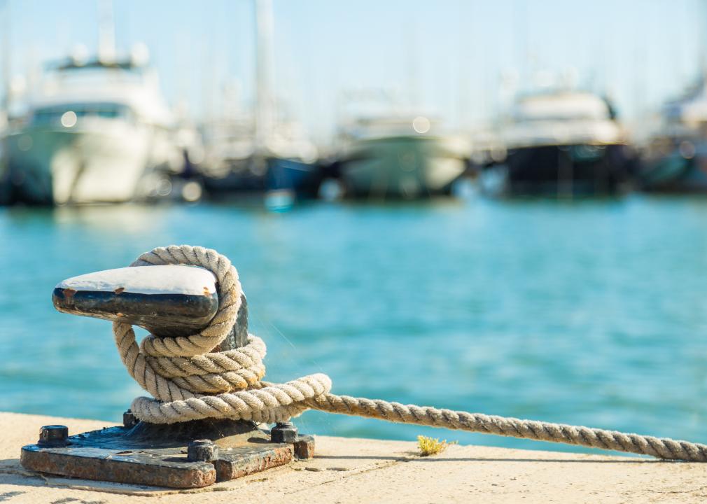 Mooring rope and bollard on water and yachts in background.