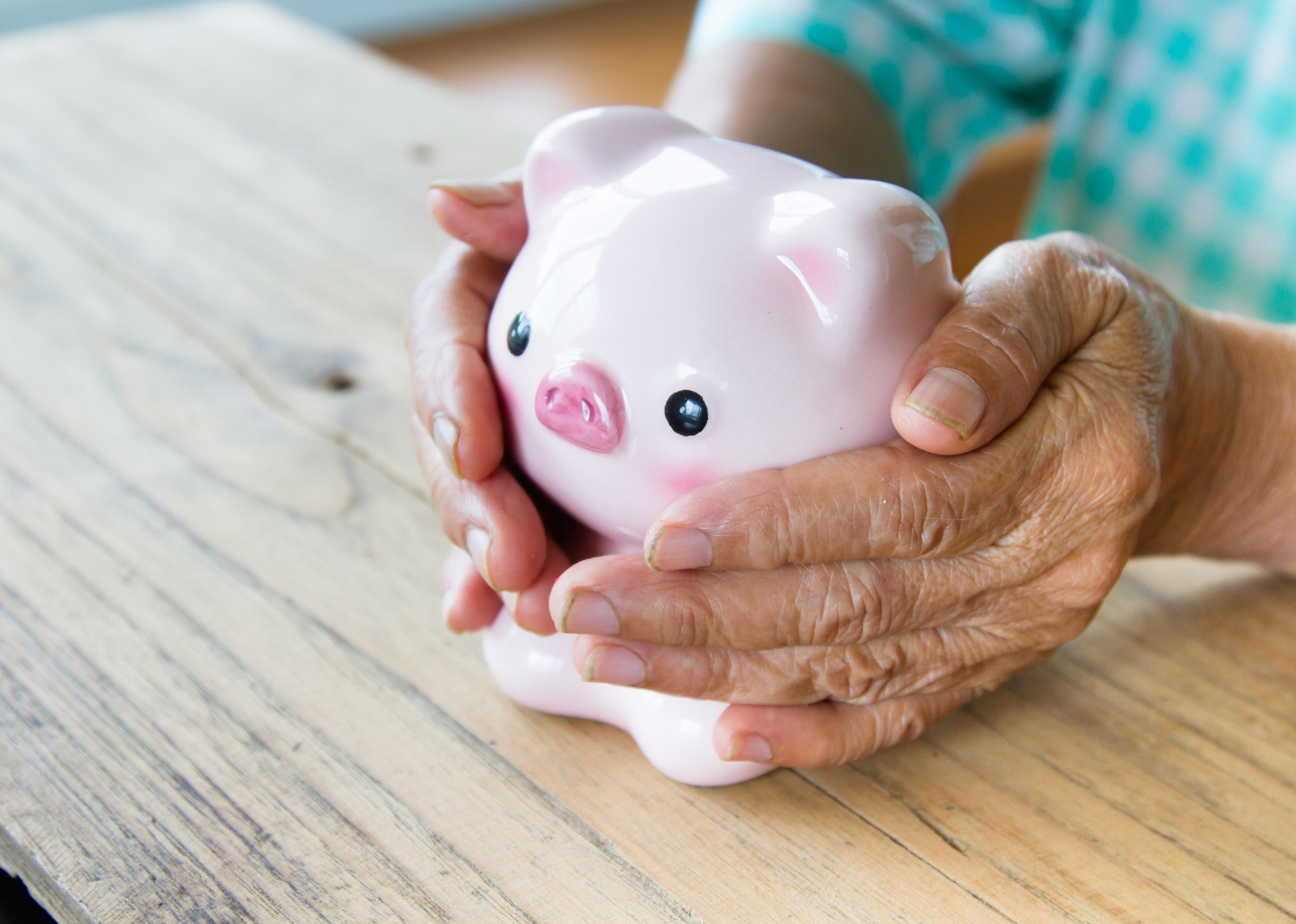 Senior's hands holding a piggy bank.