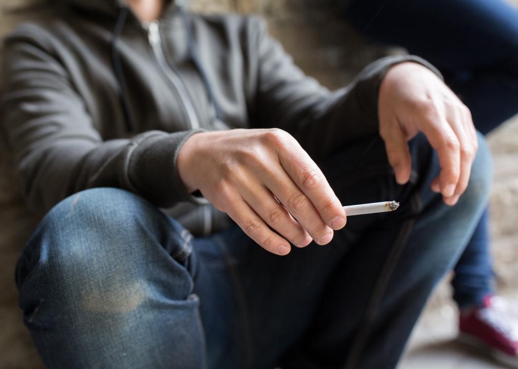 Closeup of young man smoking cigarette outdoors.