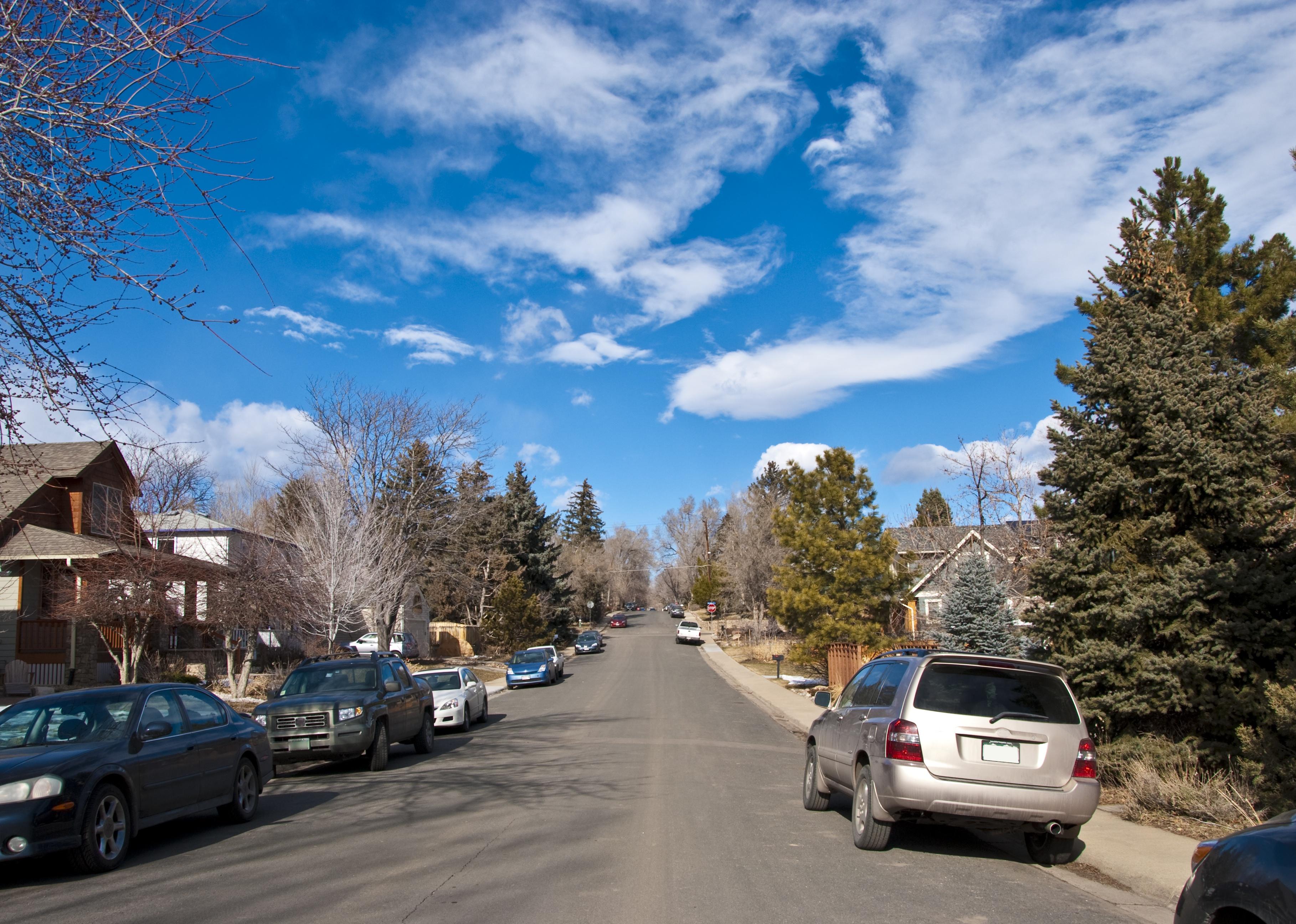 Suburban street scene with cars parked on street.
