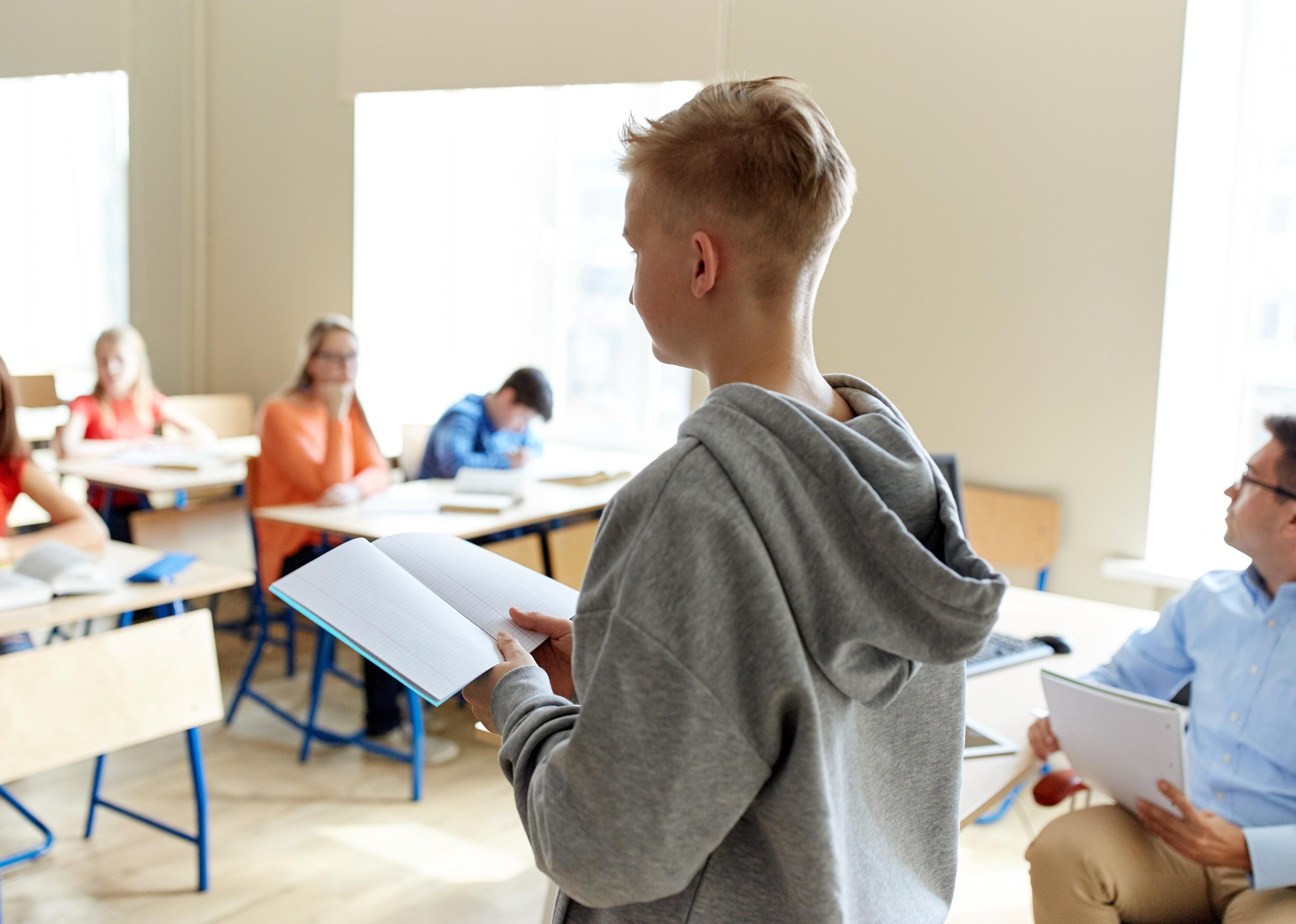 Student with book at the front of a classroom