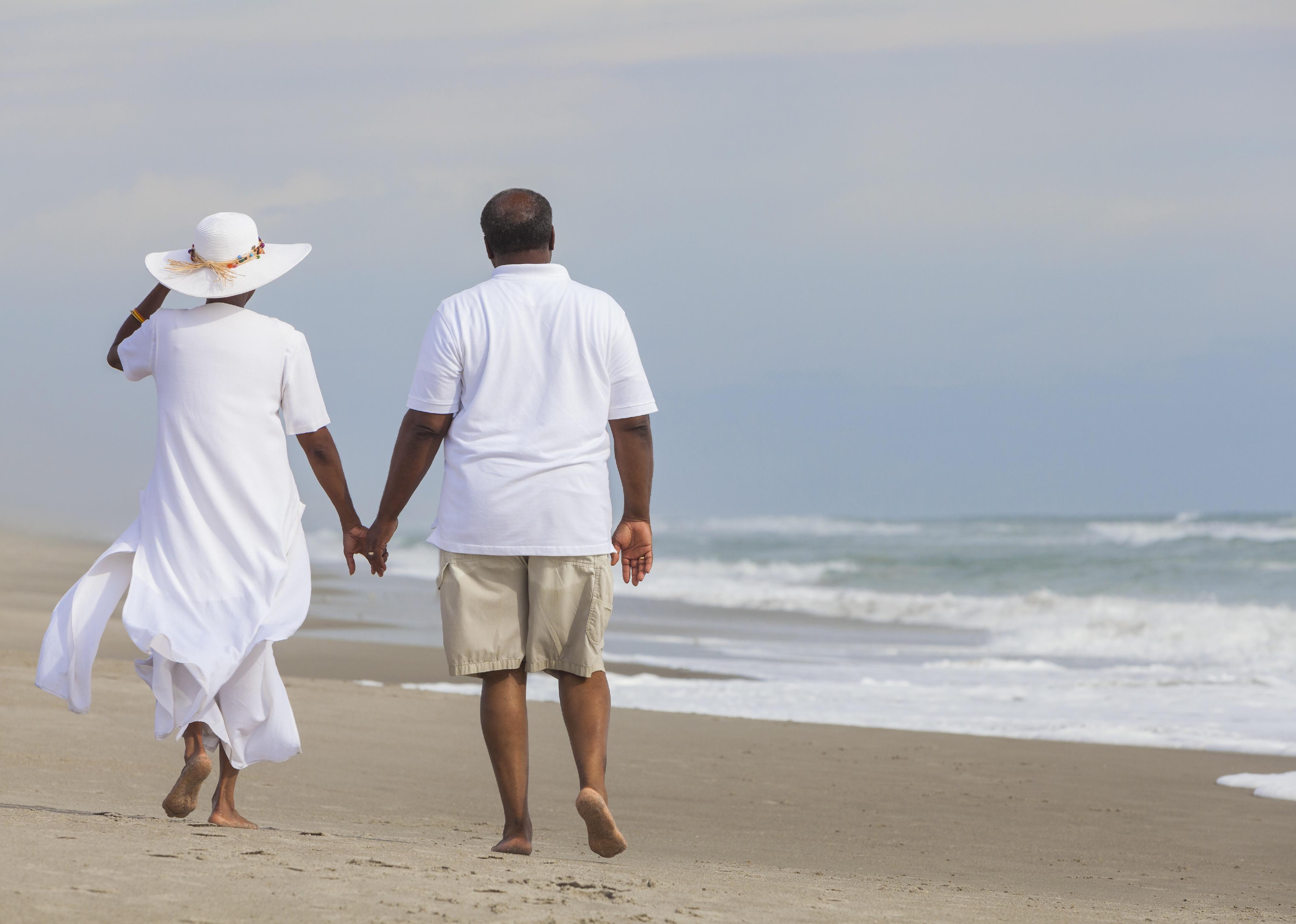 Couple walking along beach holding hands.