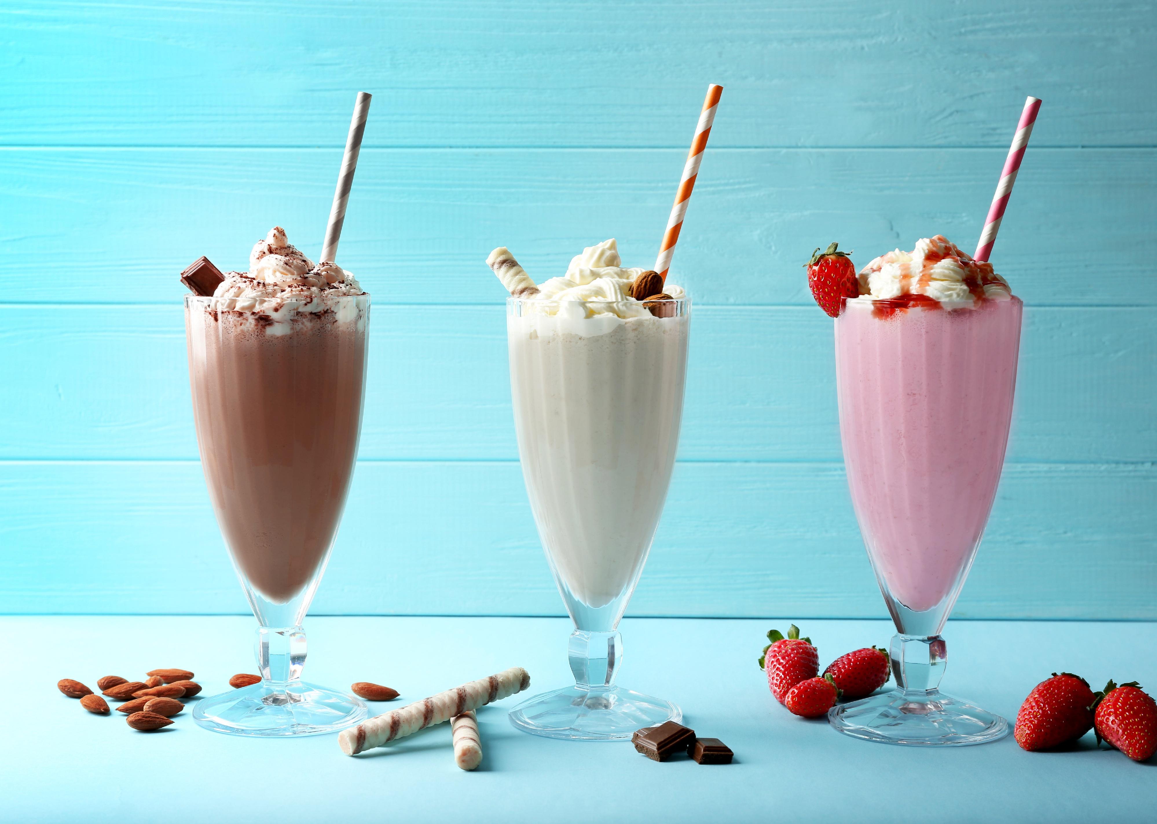 Delicious milkshakes on blue wooden background.