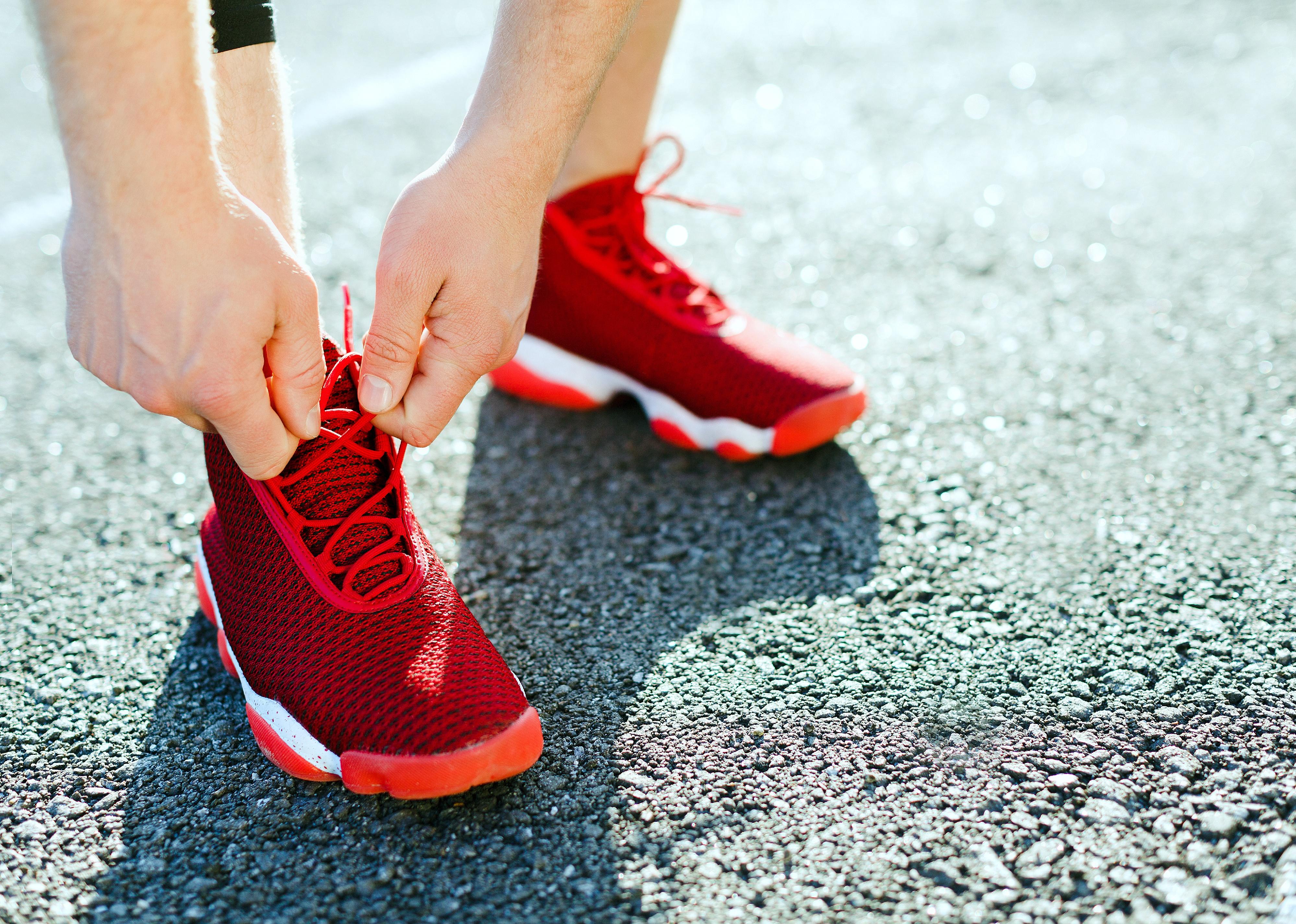 Man tightening lacings on his sneakers.