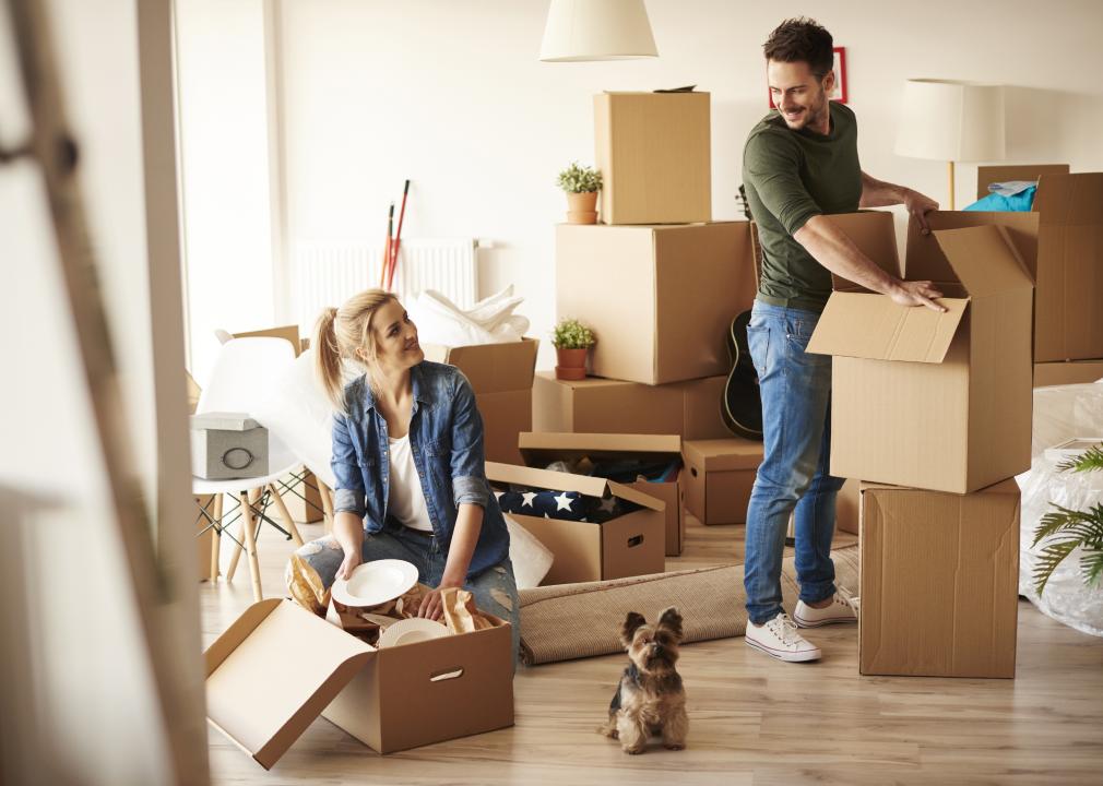 Young couple with small dog unpacking boxes 