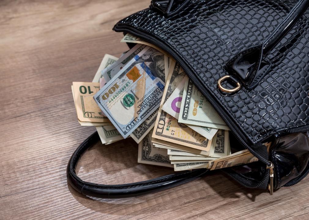 A black womans handbag full of money