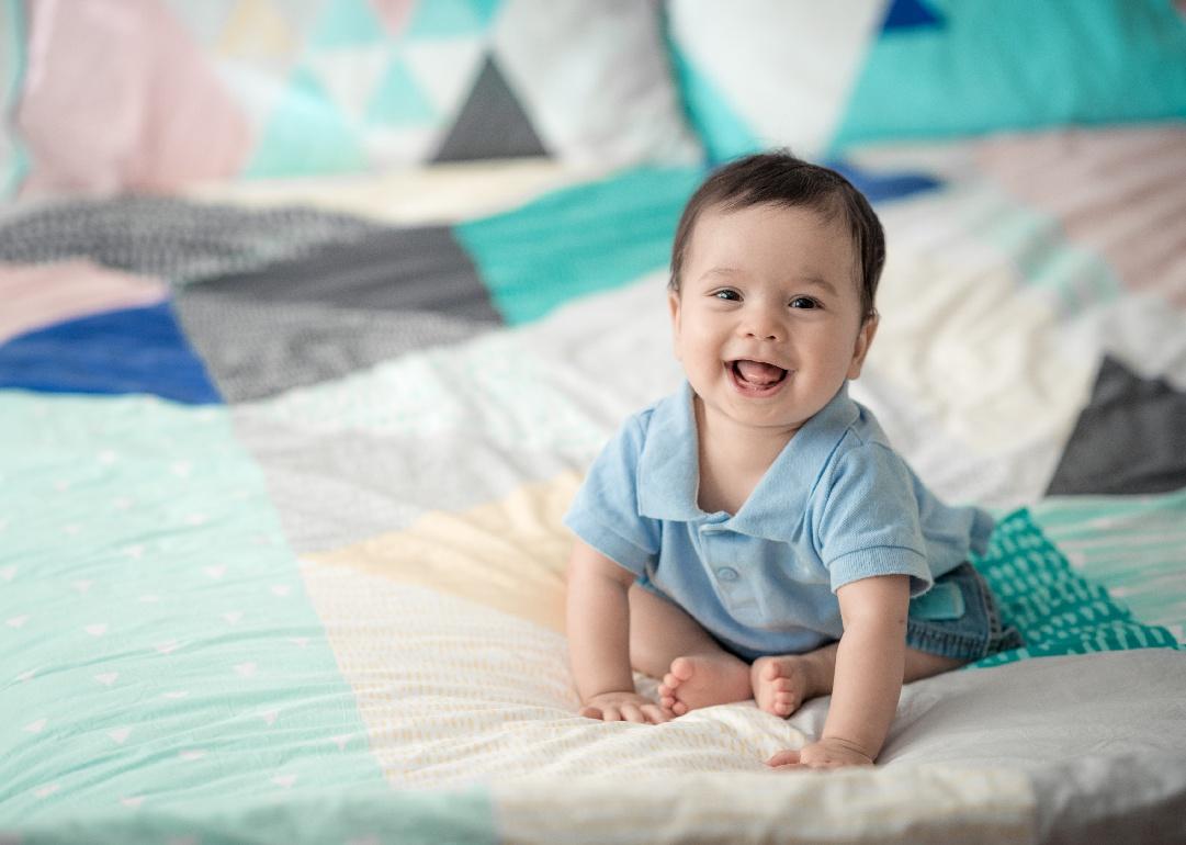 Smiling baby on multi-colored bedding.