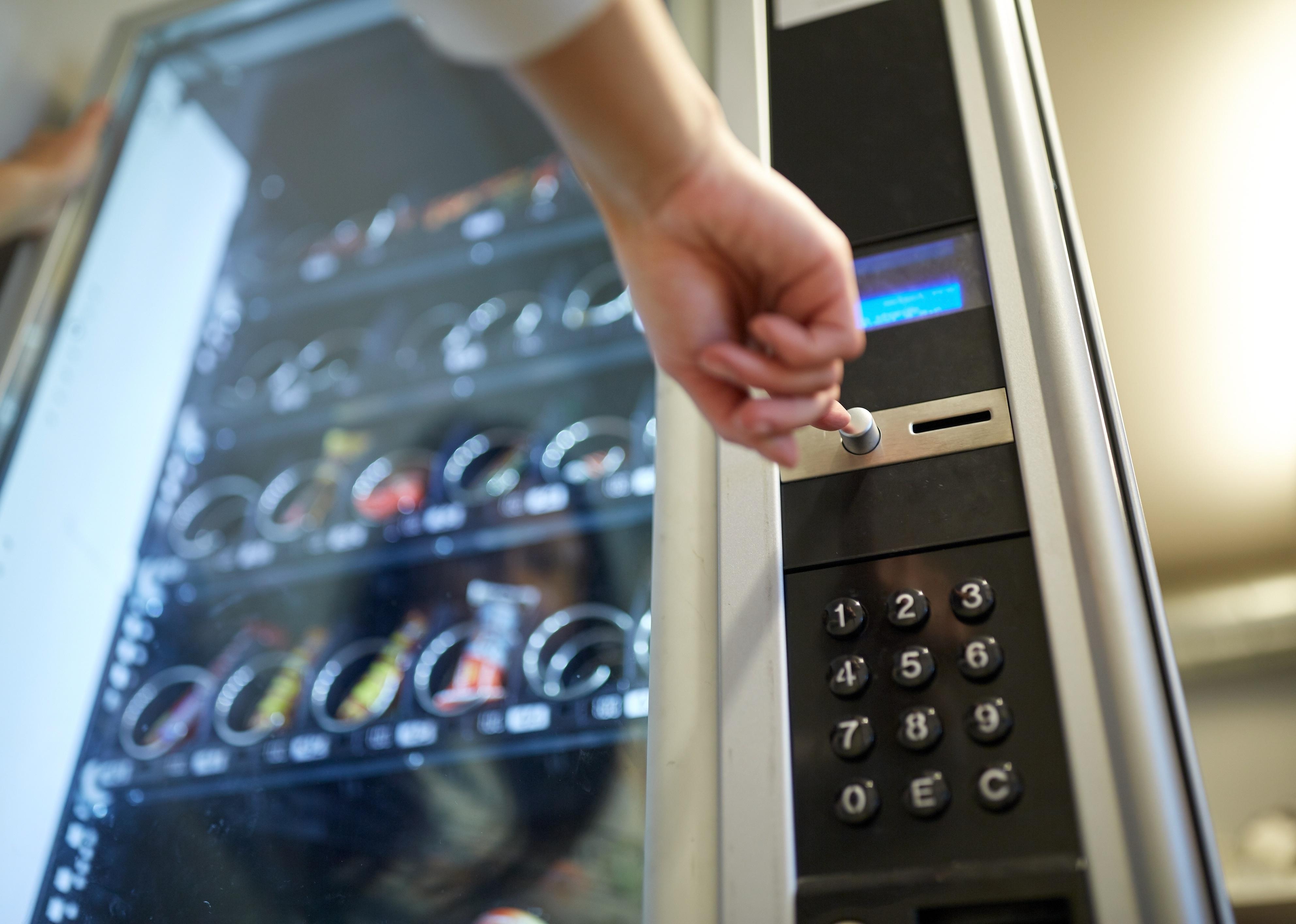 Hand pushing button on vending machine operation panel.