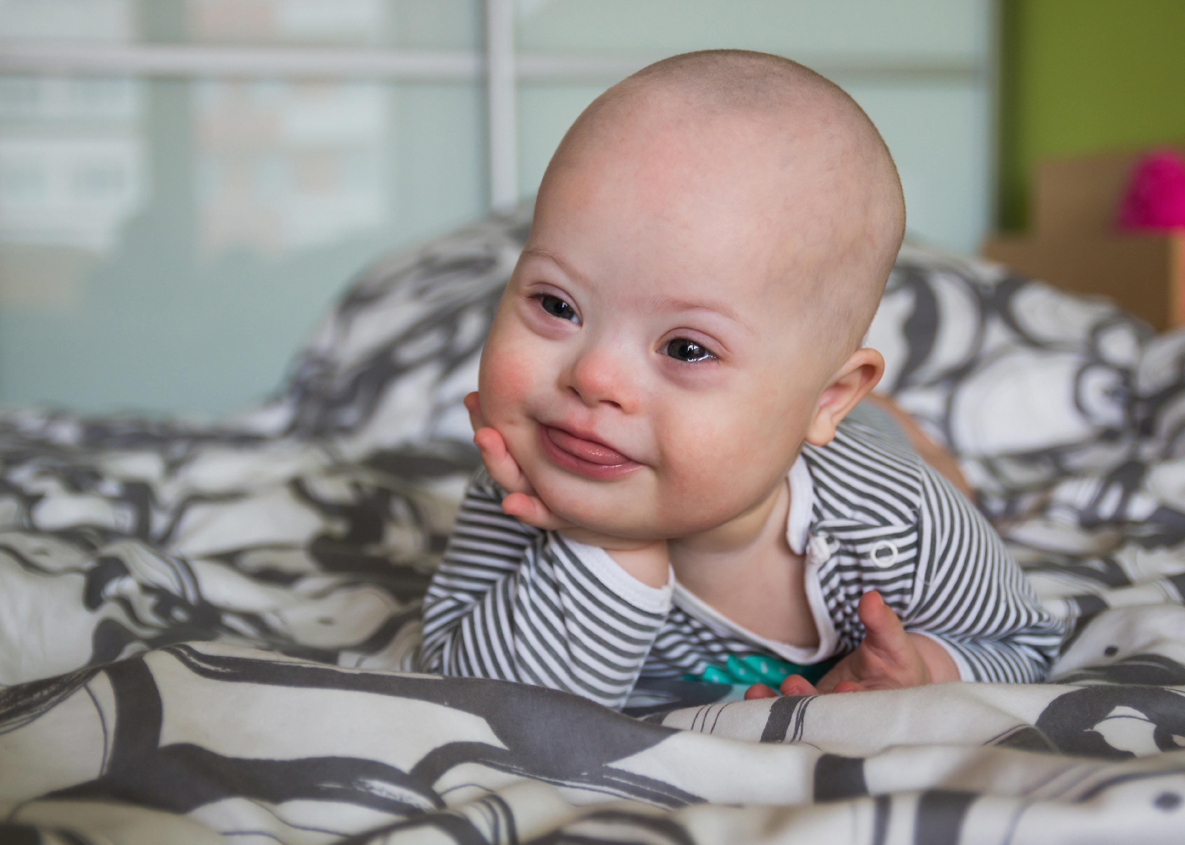 Cute baby wearing striped clothing laying on stomach.