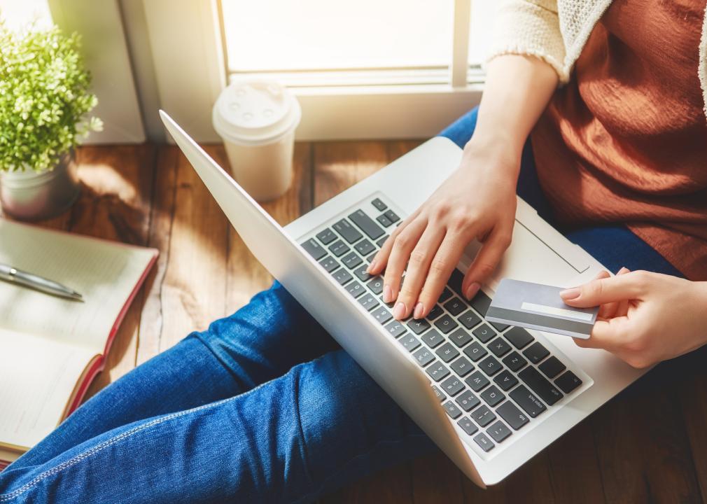 Woman is holding credit card and using laptop