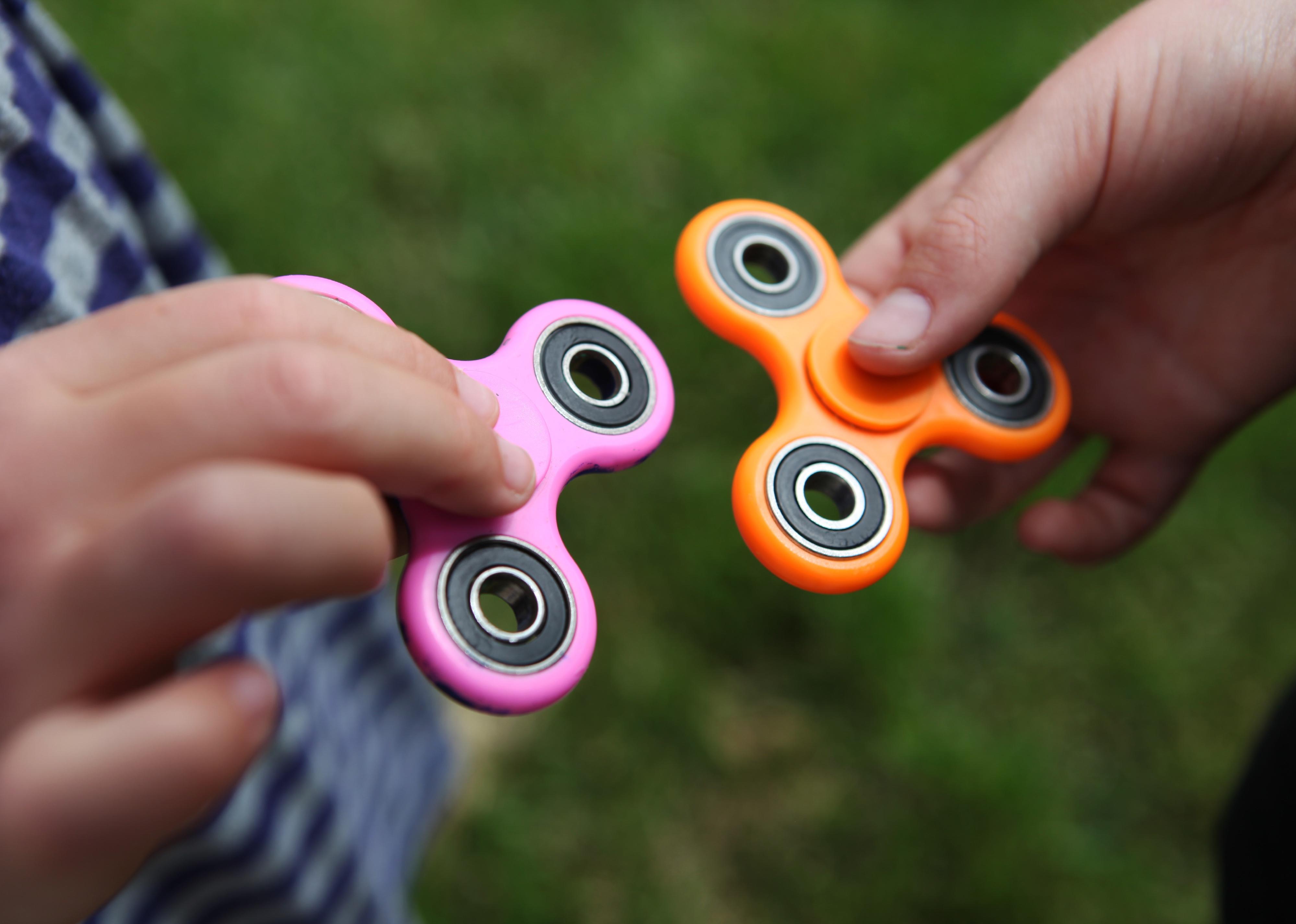 Two hands holding fidget spinners.