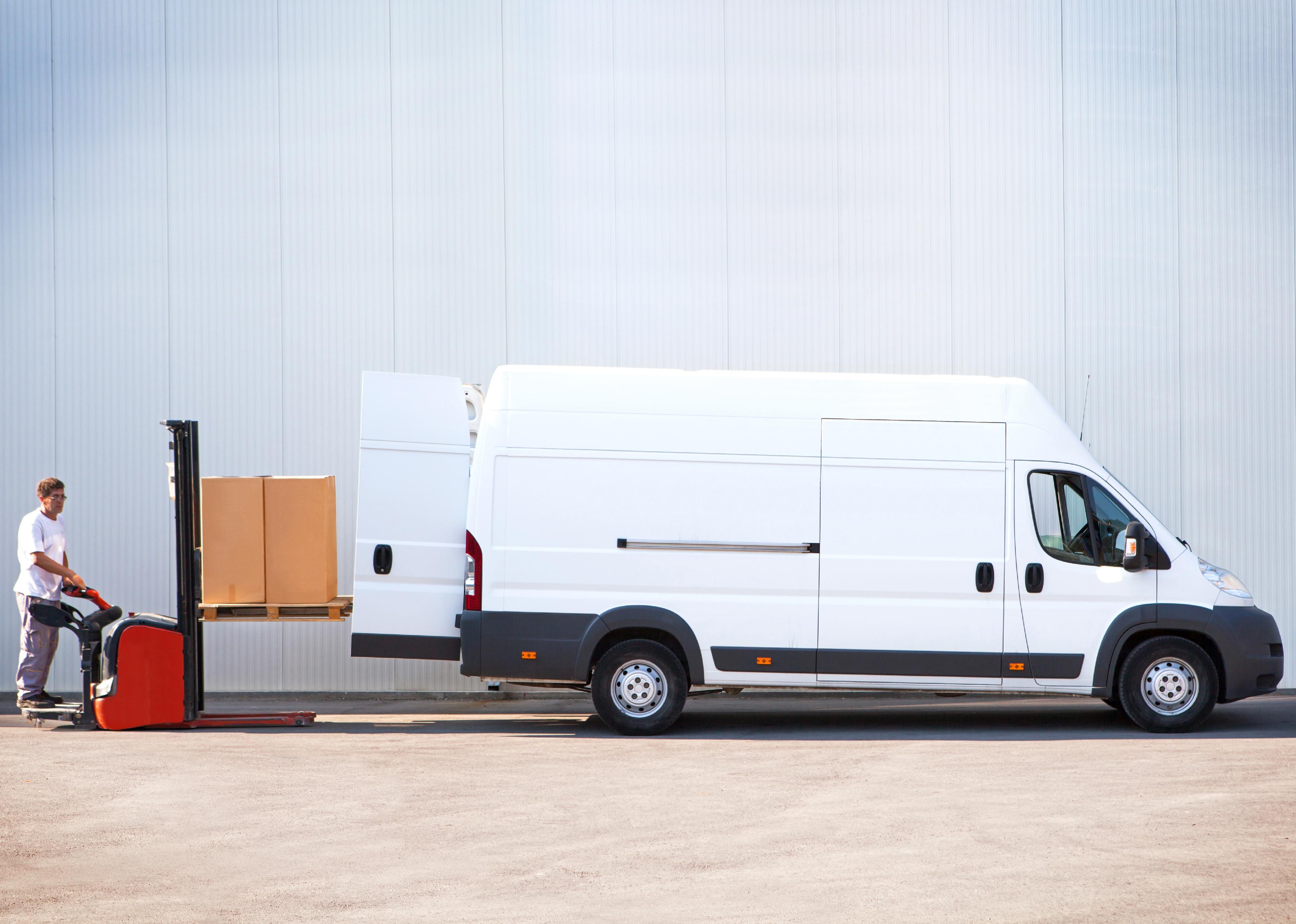 Side view of a courier loading a van with parcels.