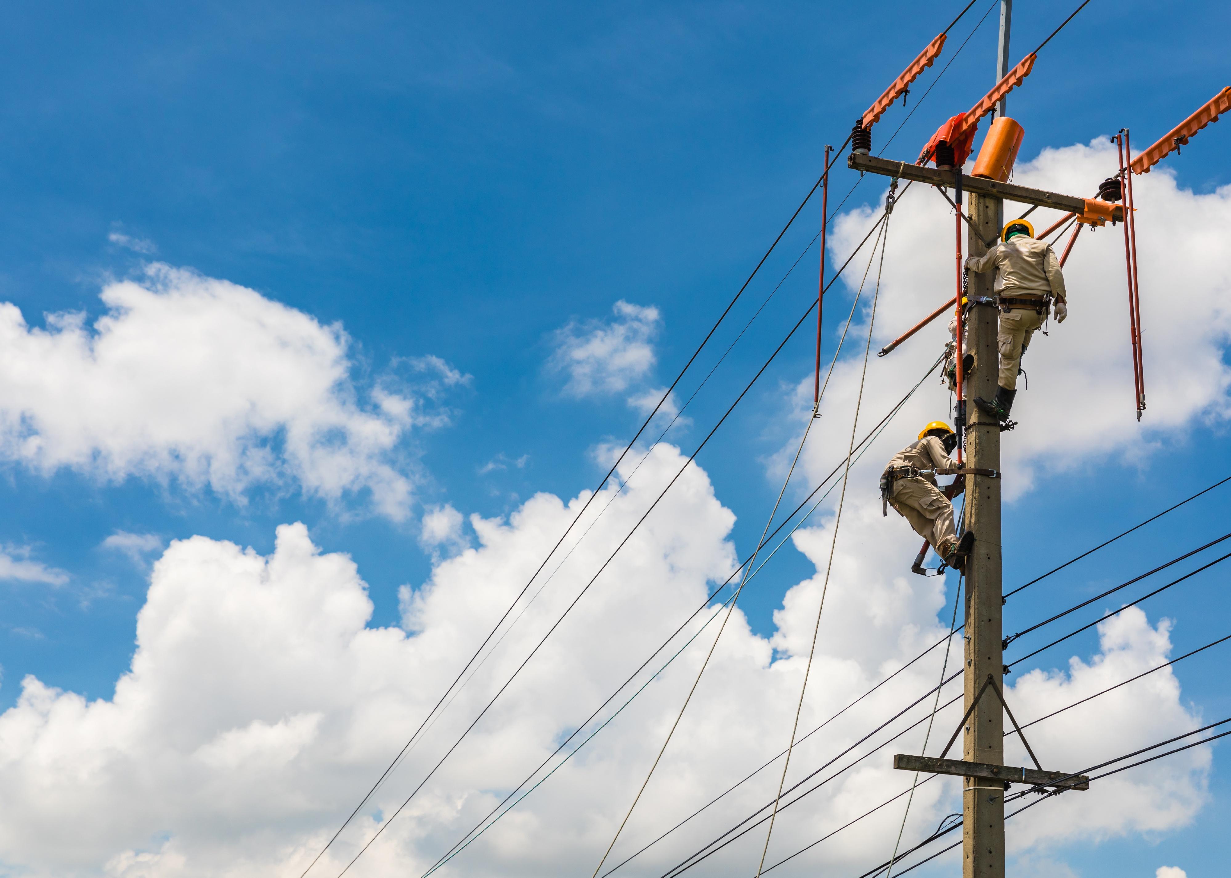 Electricians work on a power line up high.