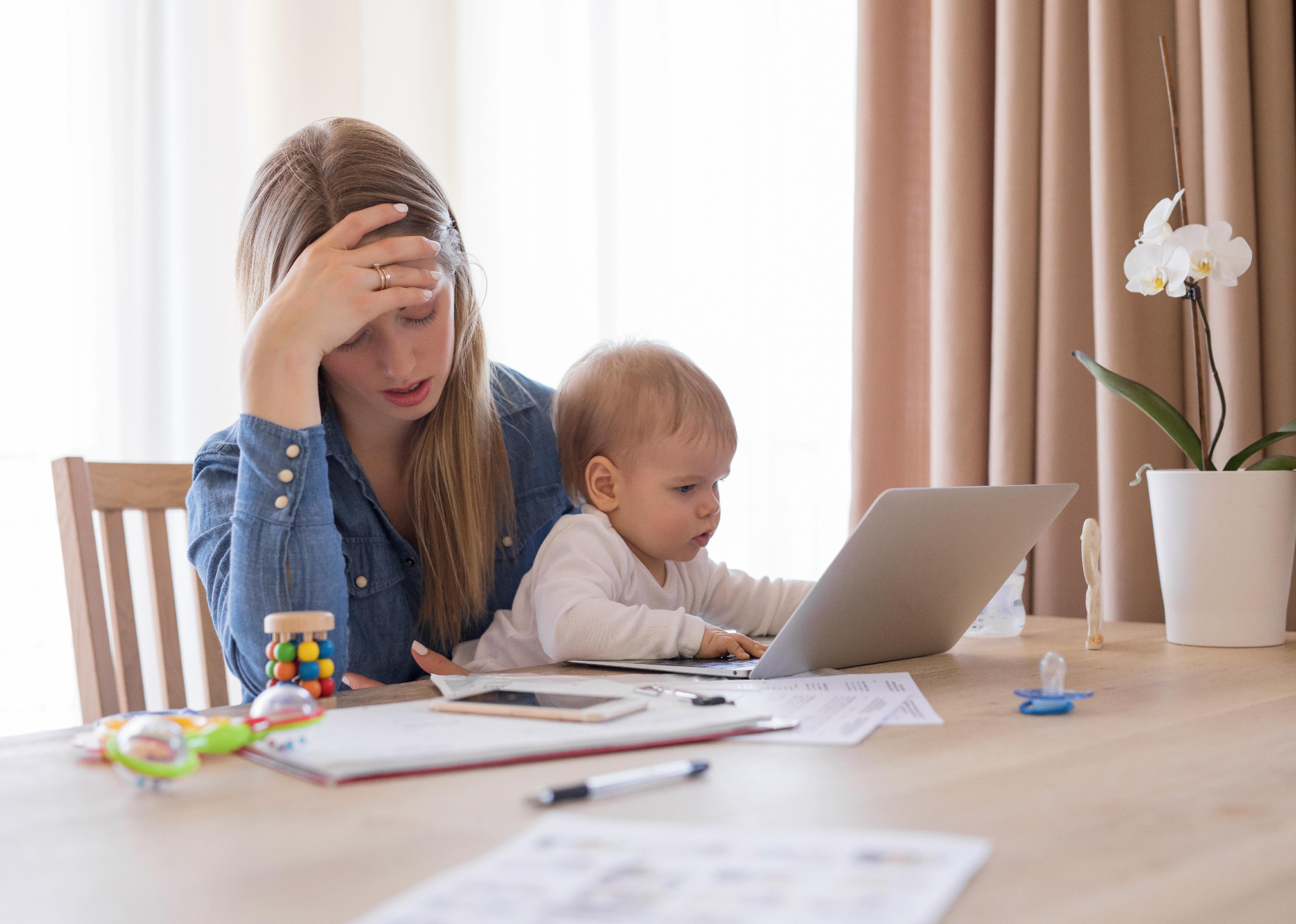 Mom and baby with laptop looking stressed