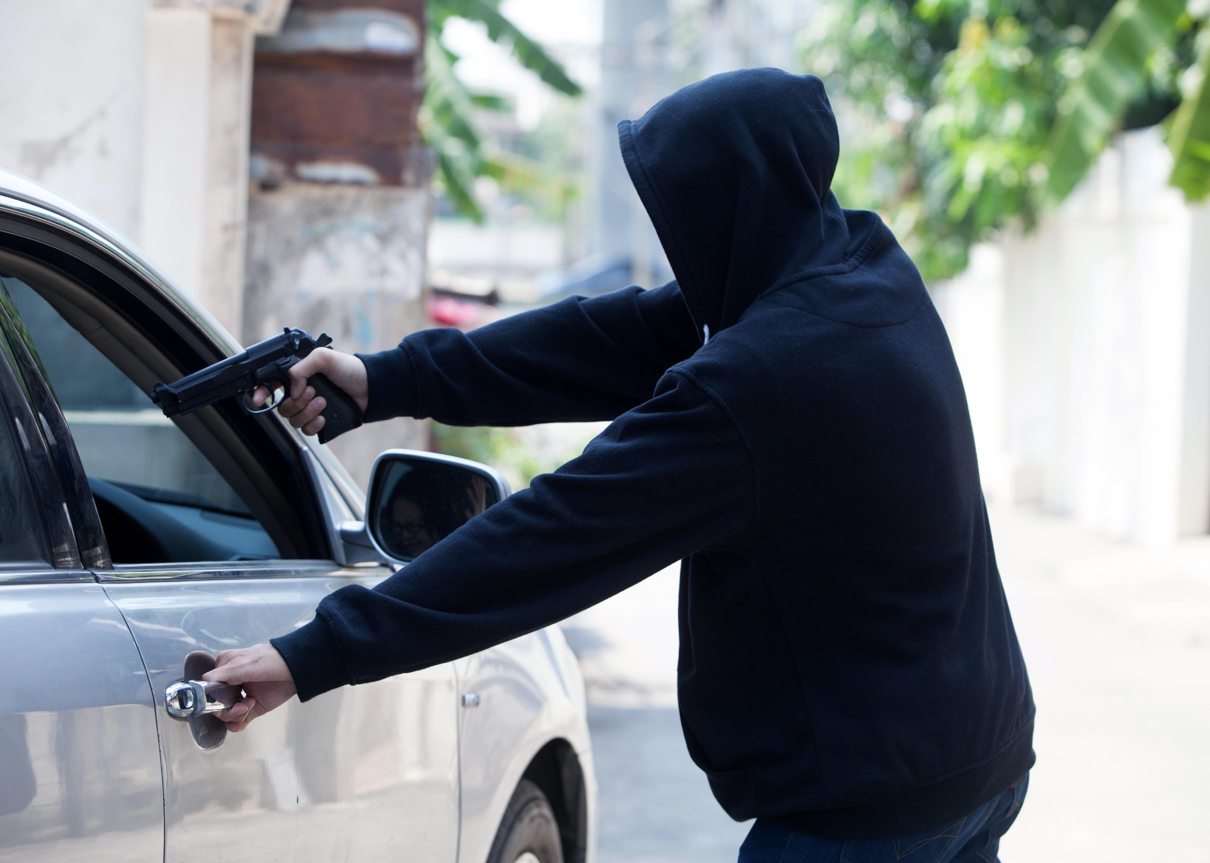 Person highjacking a car with a gun.